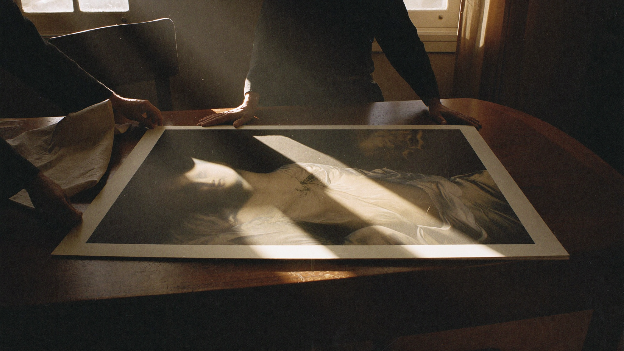 Hands holding a fine art print in golden window light