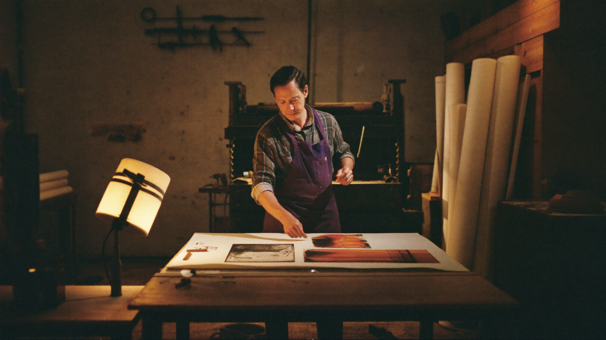 Craftsman inspecting a fine art print in a warm studio