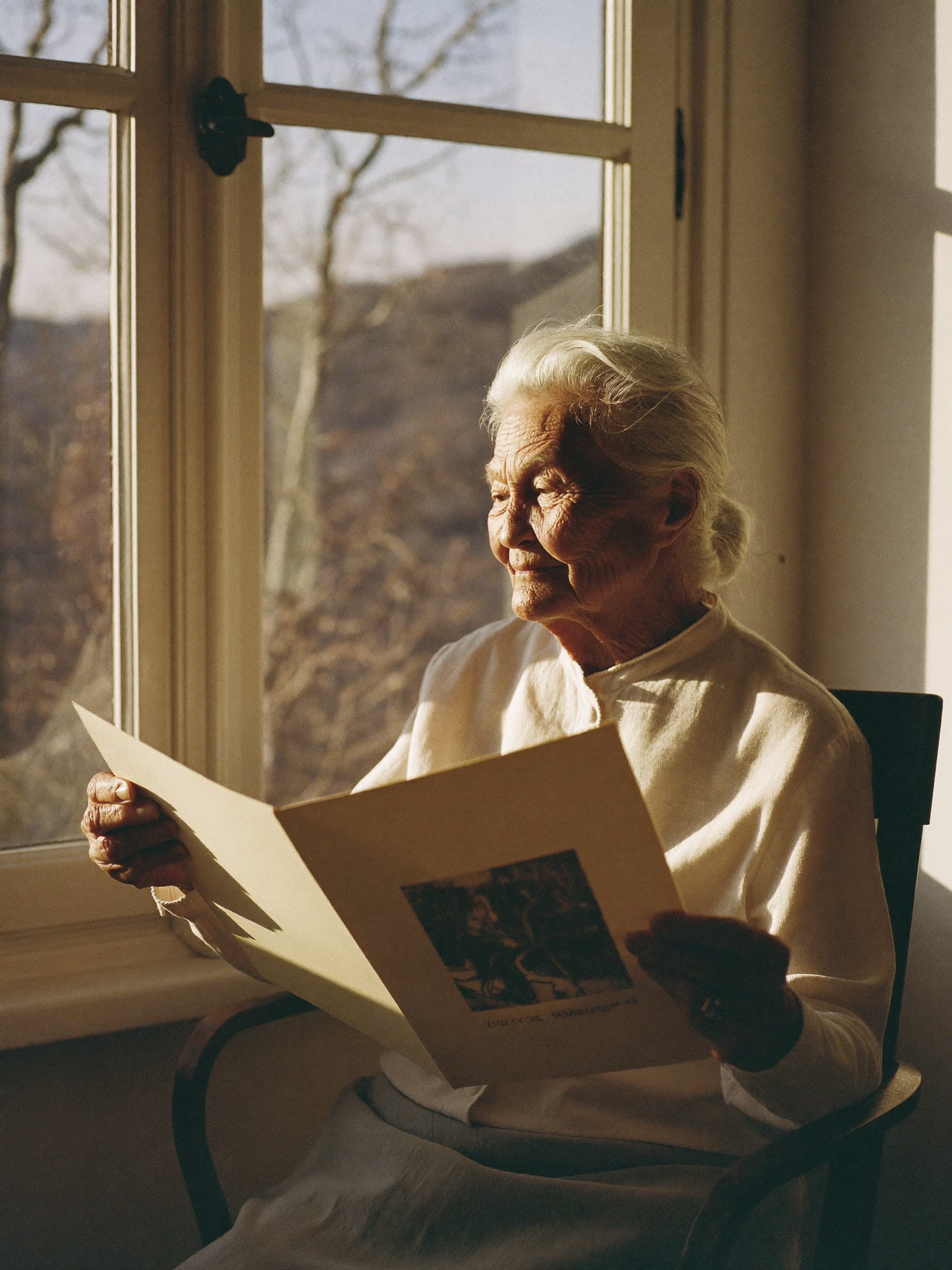 Elderly woman by a window holding a printed photograph