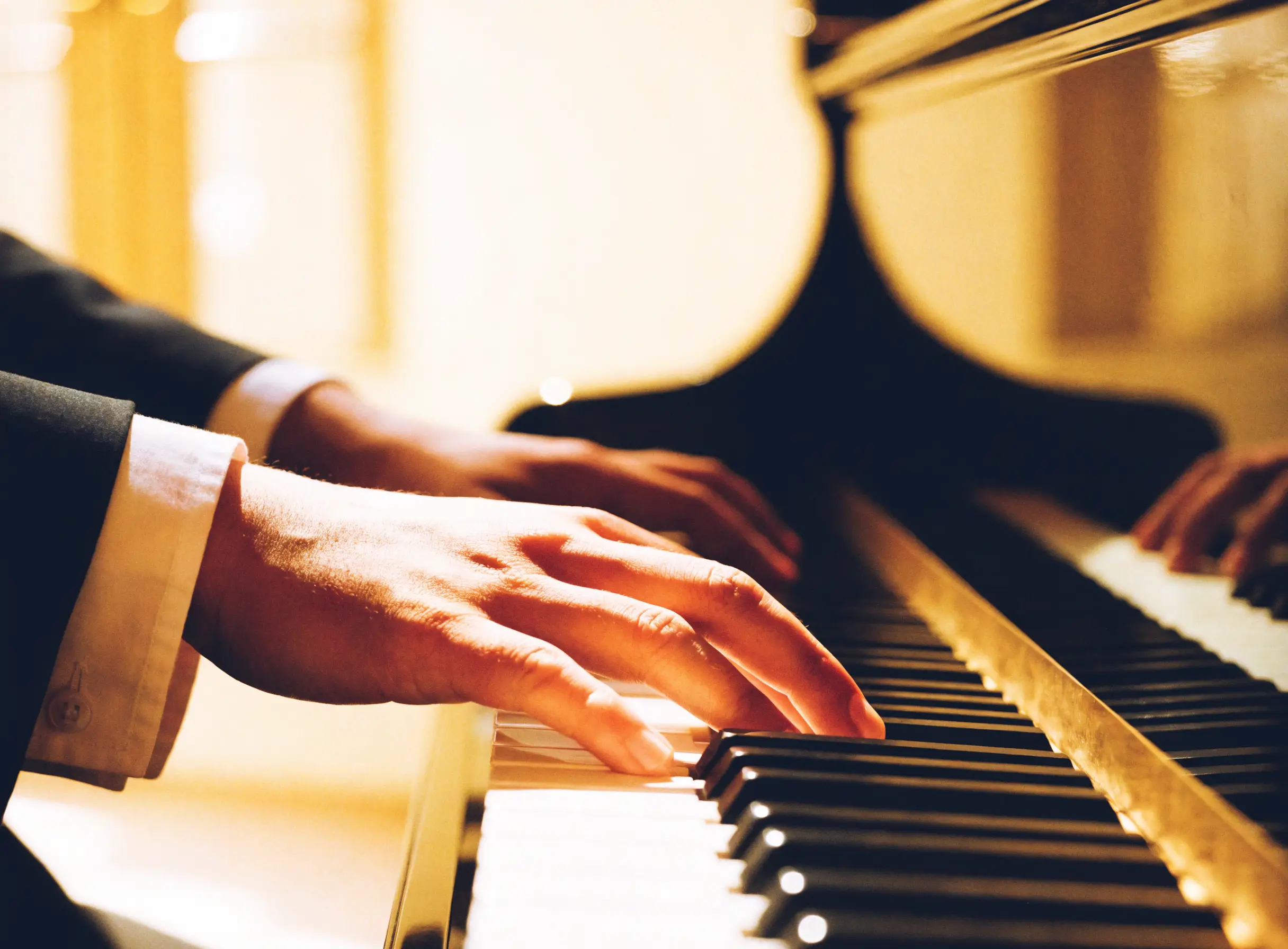Hands playing a grand piano