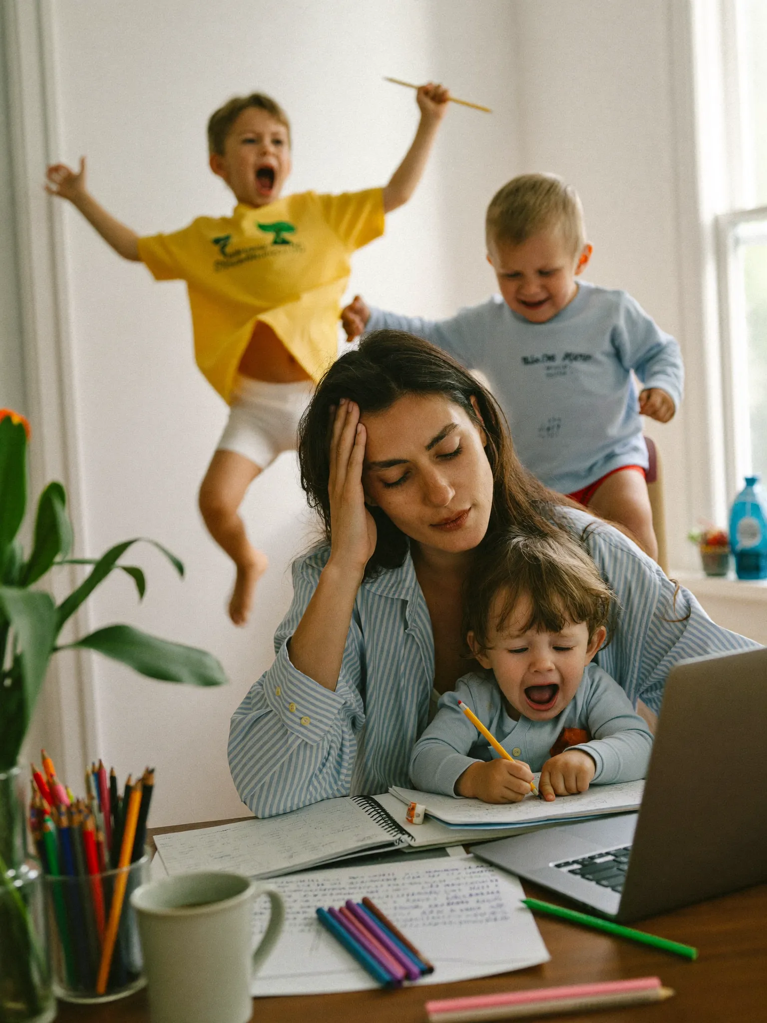 Overwhelmed mom at her desk, toddler on her lap
