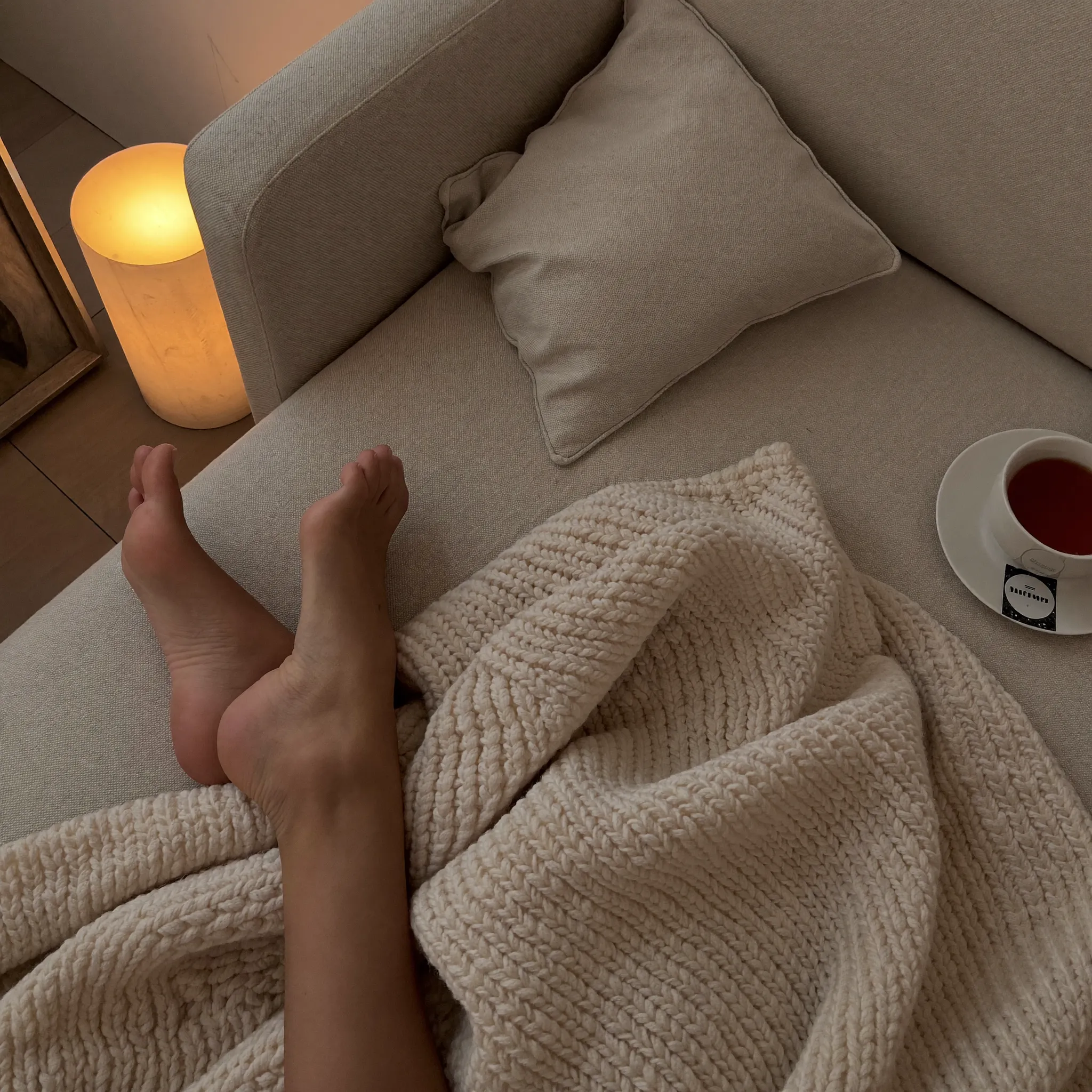 Bare feet tucked under a knit blanket on the couch
