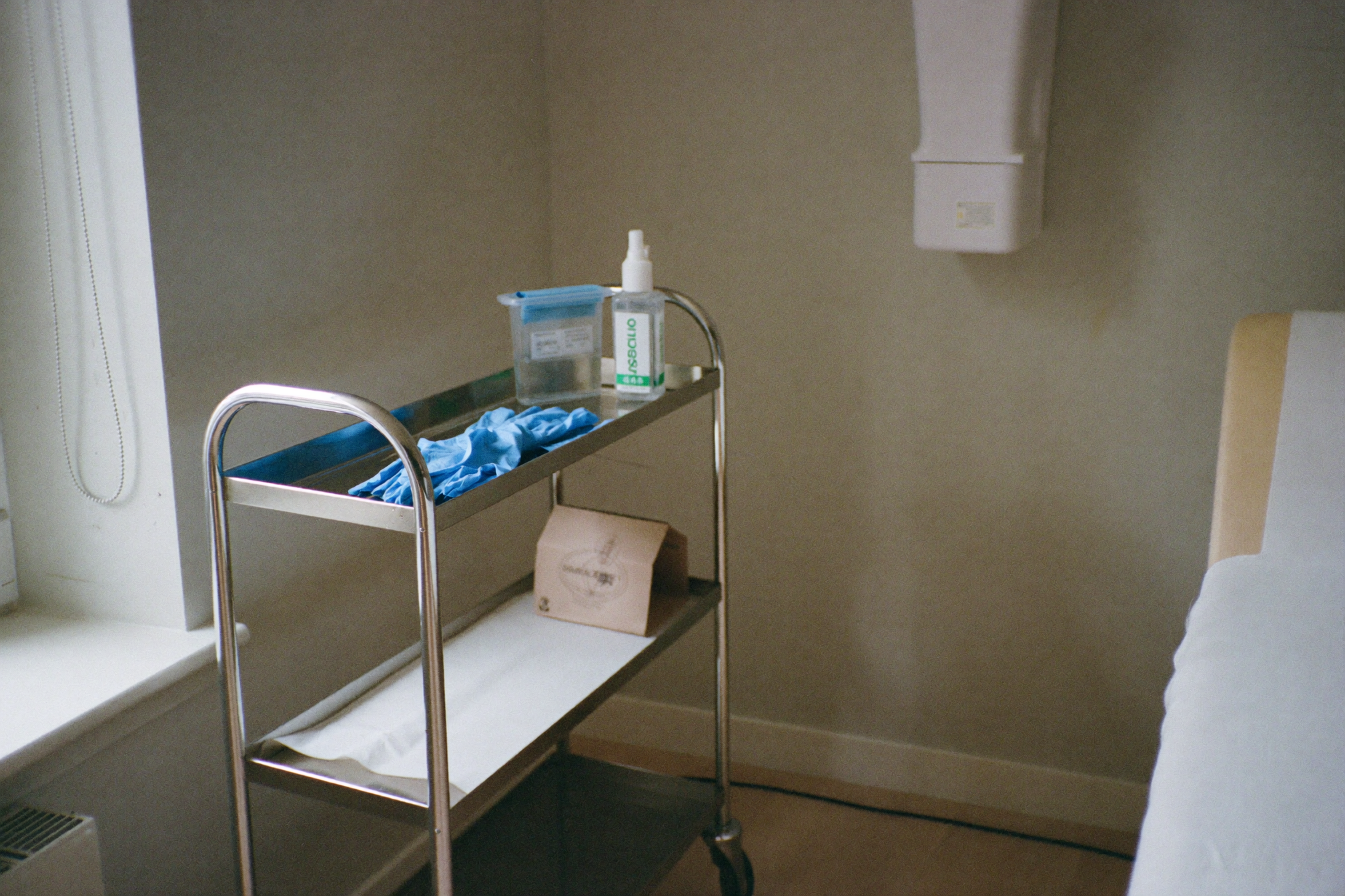 A clinic treatment room with a stocked supply trolley beside the bed