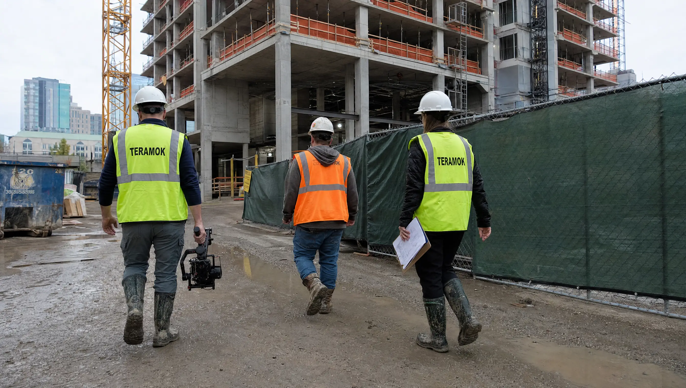 TERAMOK production crew in green safety vests and hard hats walking a Dallas high-rise construction site with a gimbal camera and shot list, new development marketing in Dallas