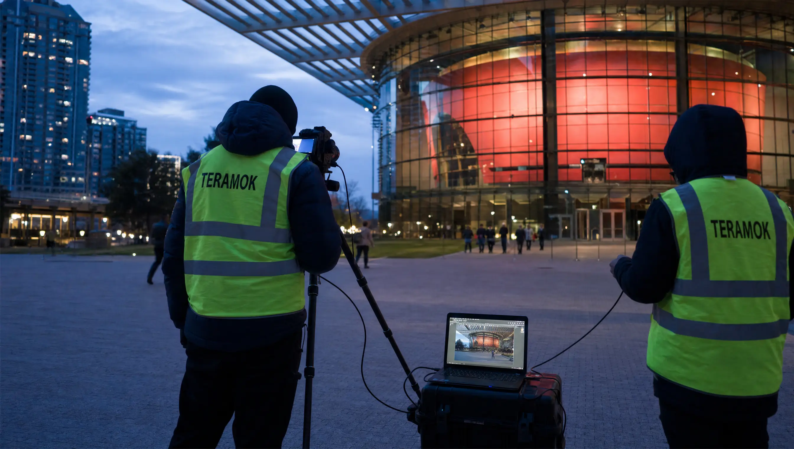 TERAMOK architectural photographer in a green safety vest photographing the Winspear Opera House in the Dallas Arts District at blue hour with a tethered laptop, marketing for architects in Dallas