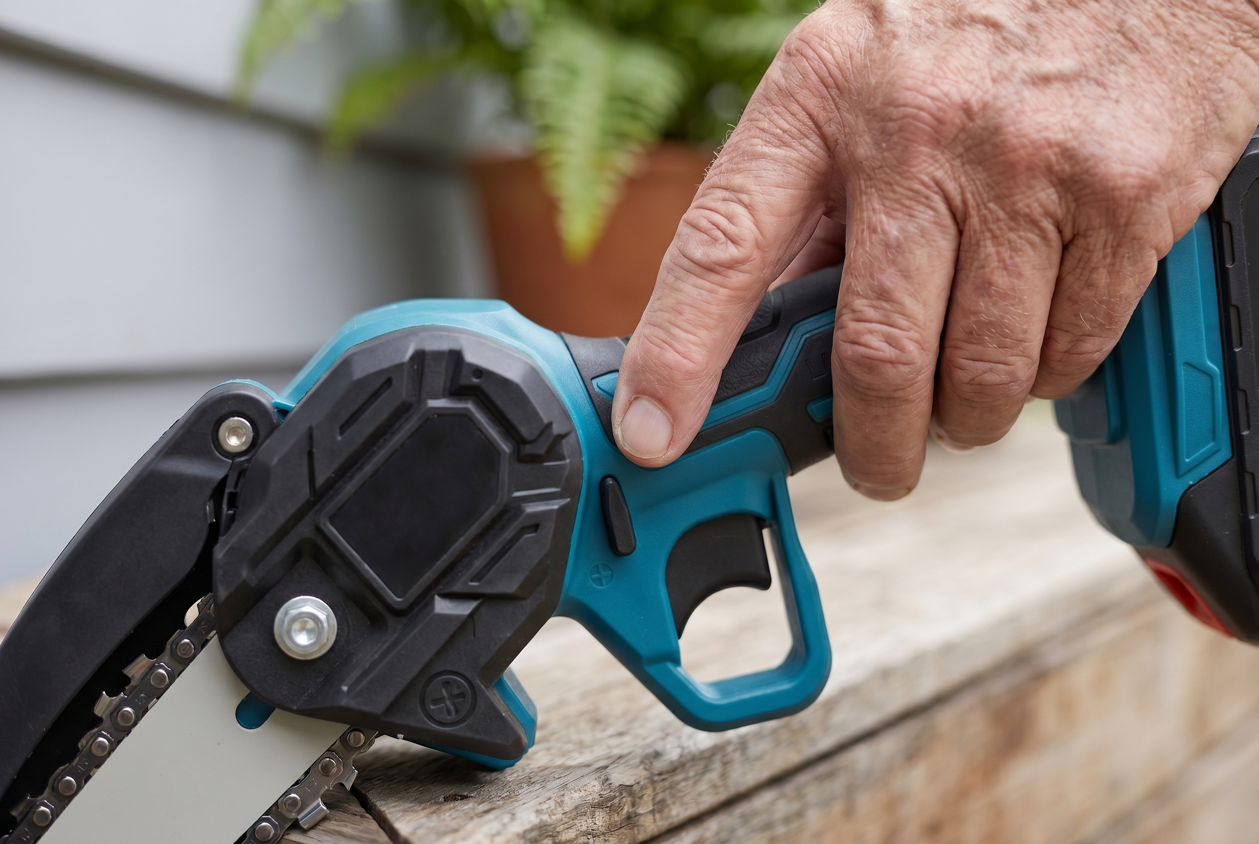Finger pressing the one-button start on the mini chainsaw