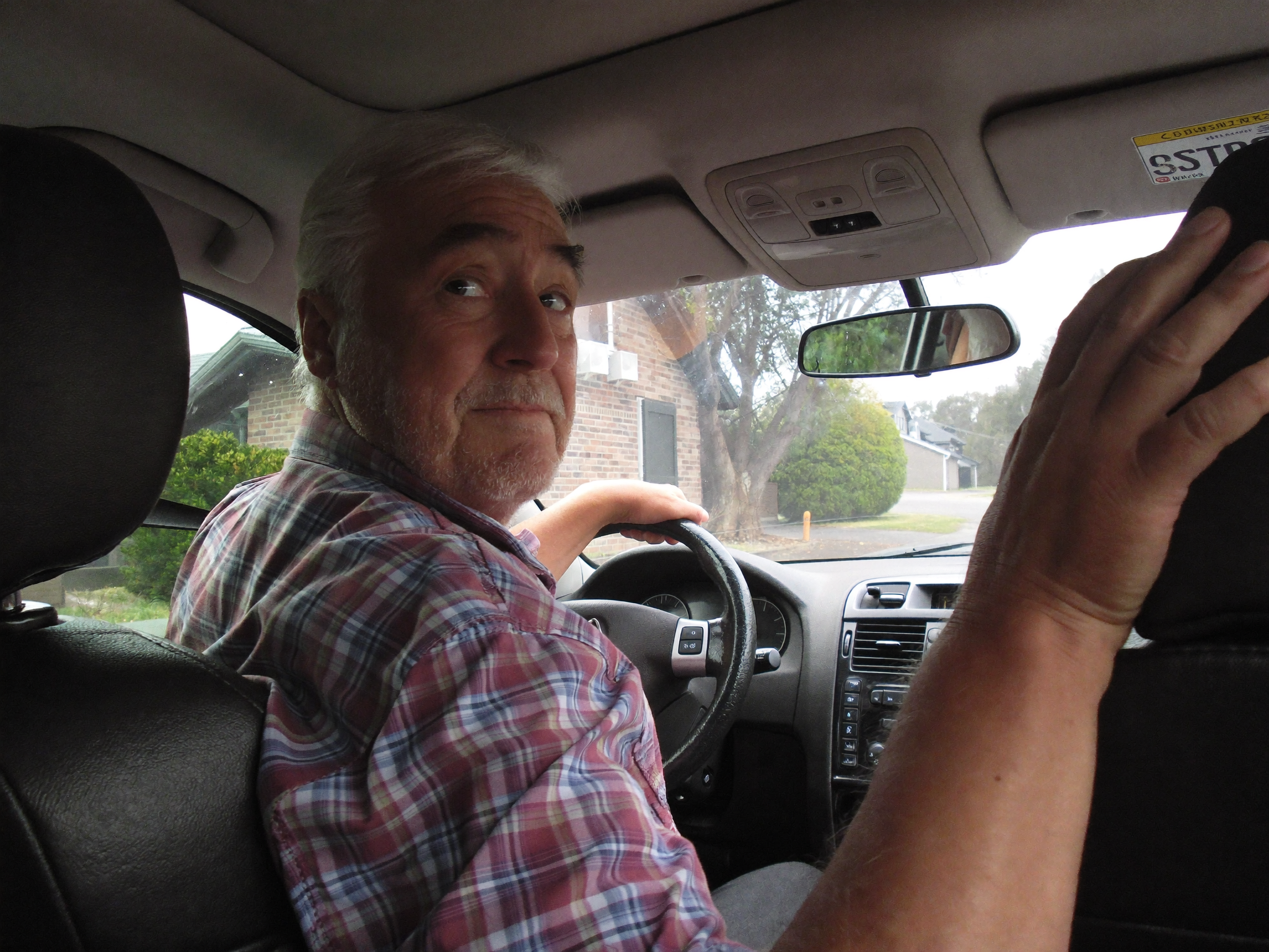 Ray twisting to look over his shoulder while reversing out of his driveway