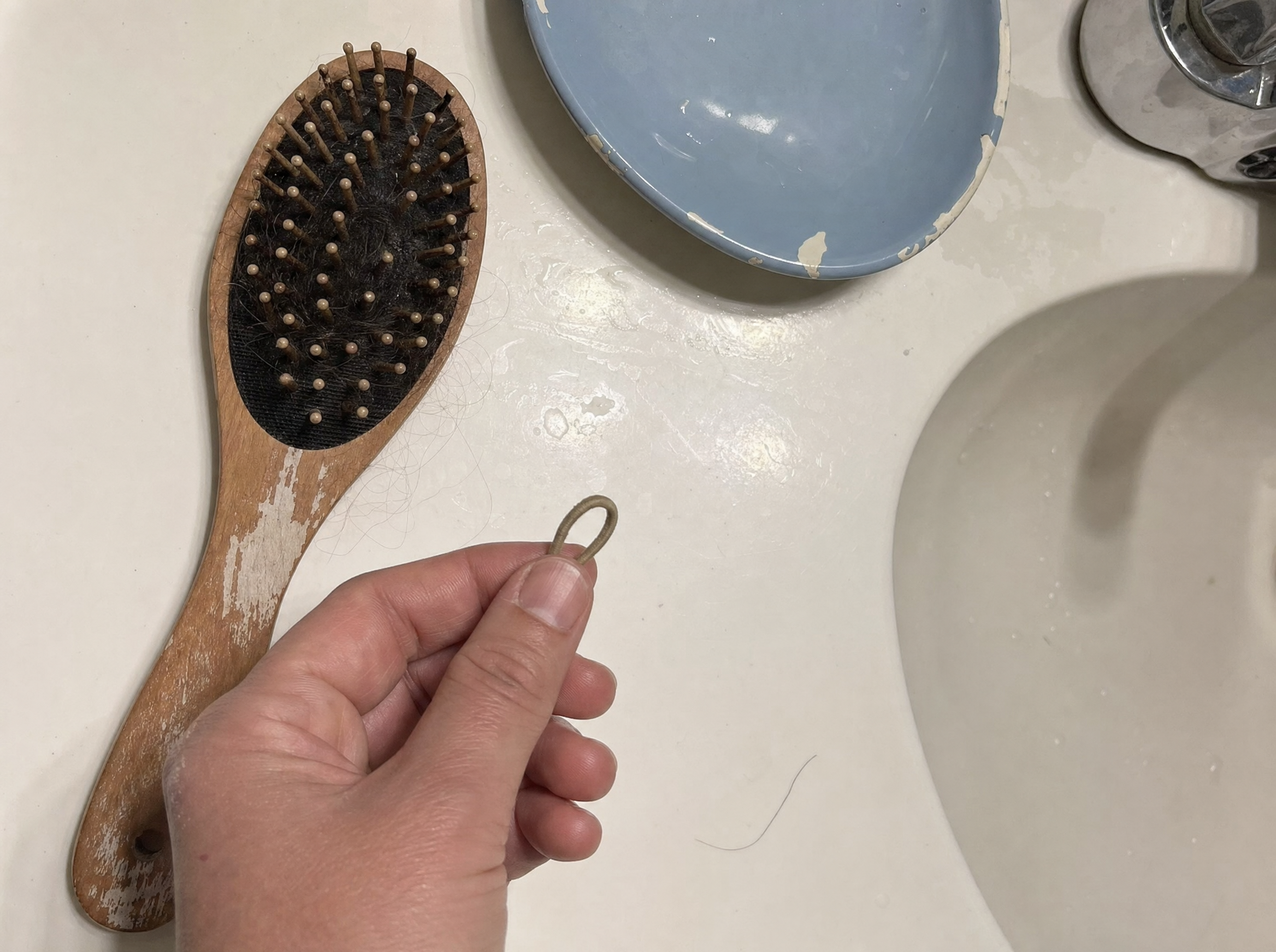 Illustrative phone photo of a small hair elastic and a brush on a bathroom counter