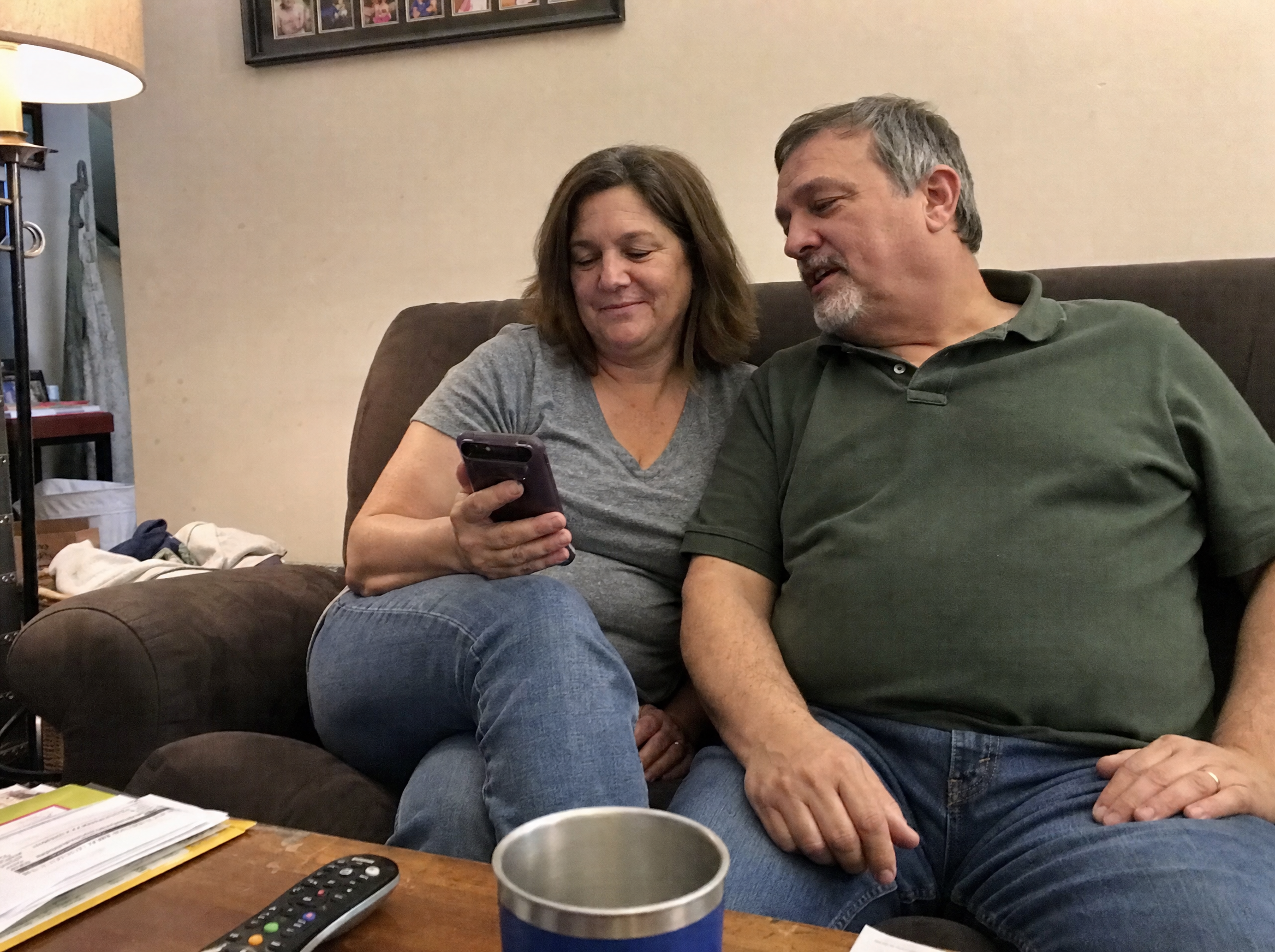 Illustrative casual phone photo of a couple looking at a phone together at home