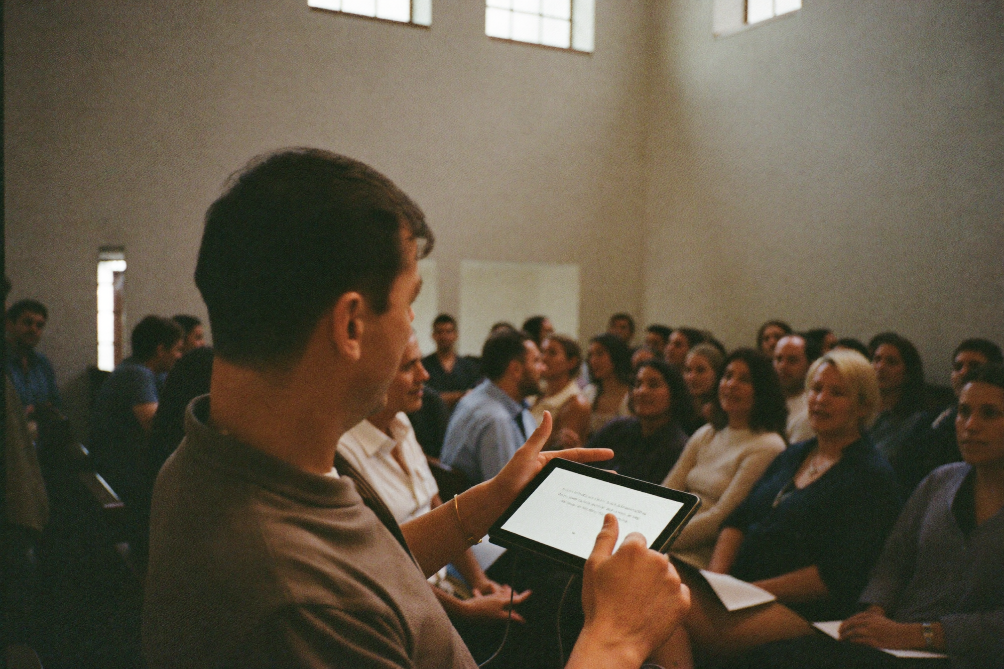 A pastor speaking to a seated congregation, mid-gesture