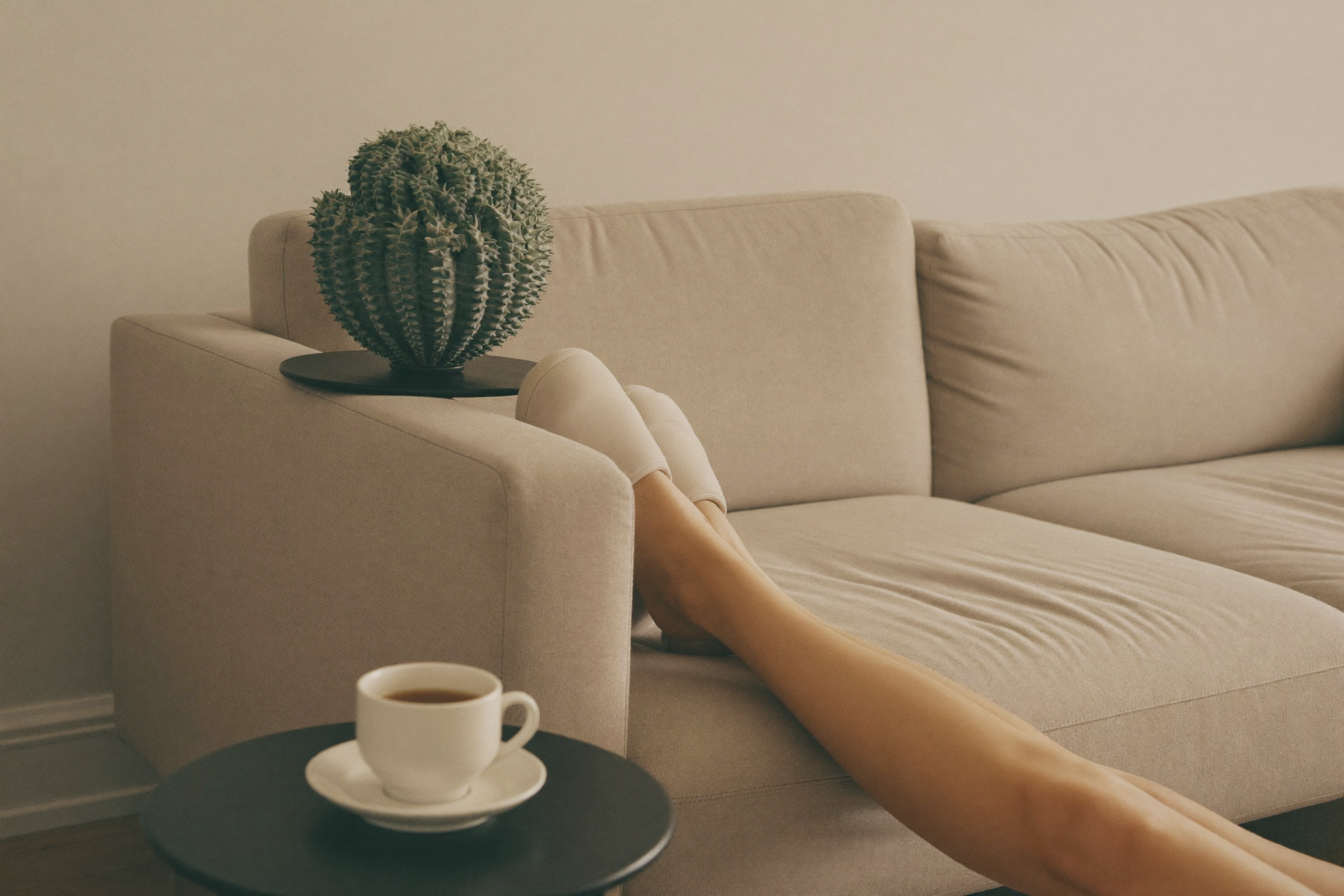 Person relaxing on a sofa with feet up wearing massage slippers, tea nearby