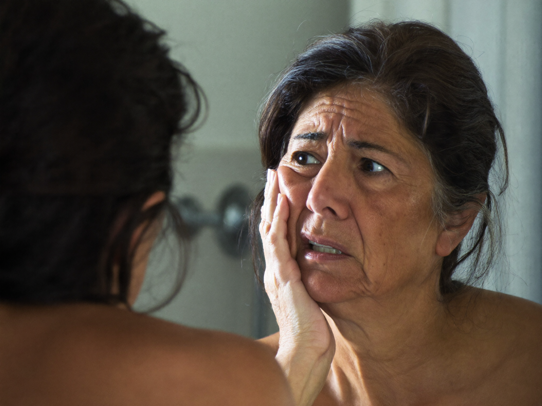 Mulher ao espelho a reparar nas rugas