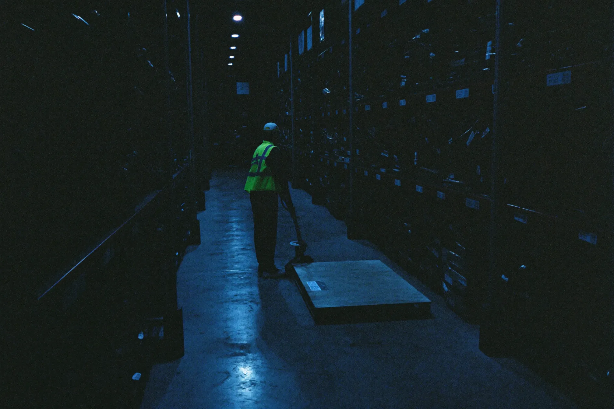 A warehouse worker moving a pallet during a night shift