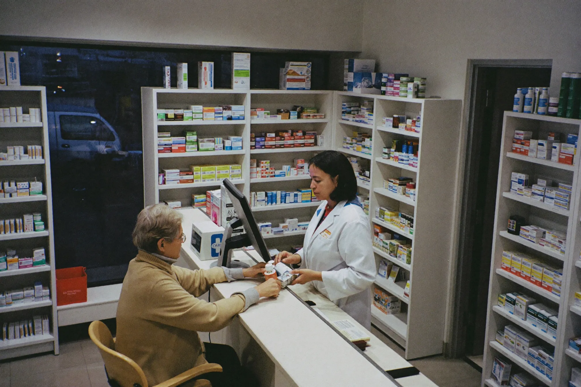 A pharmacist serving a customer in the evening