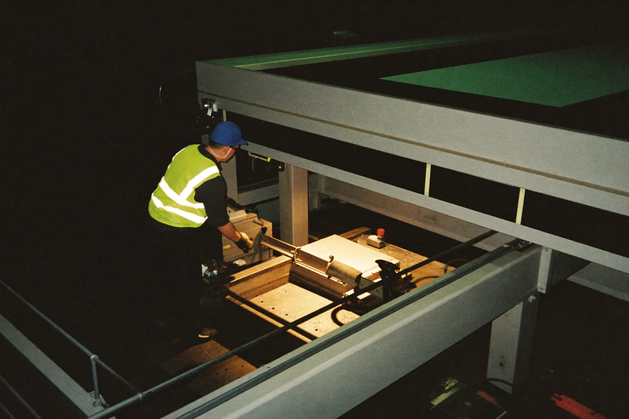 A technician inspecting a machine on a factory floor at night