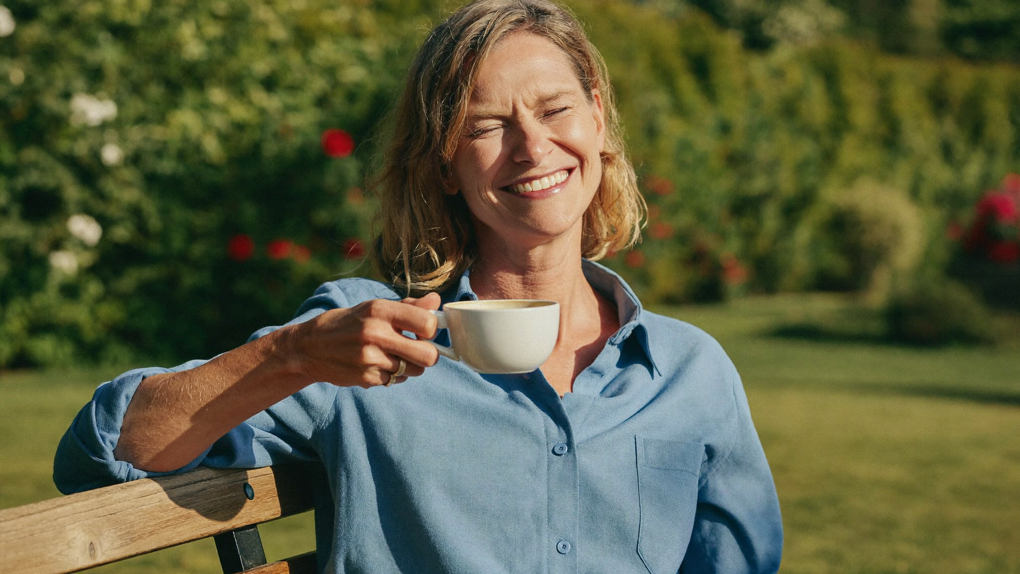 Pflegende Angehörige entspannt mit einer Tasse Kaffee auf einer Gartenbank im Sommer