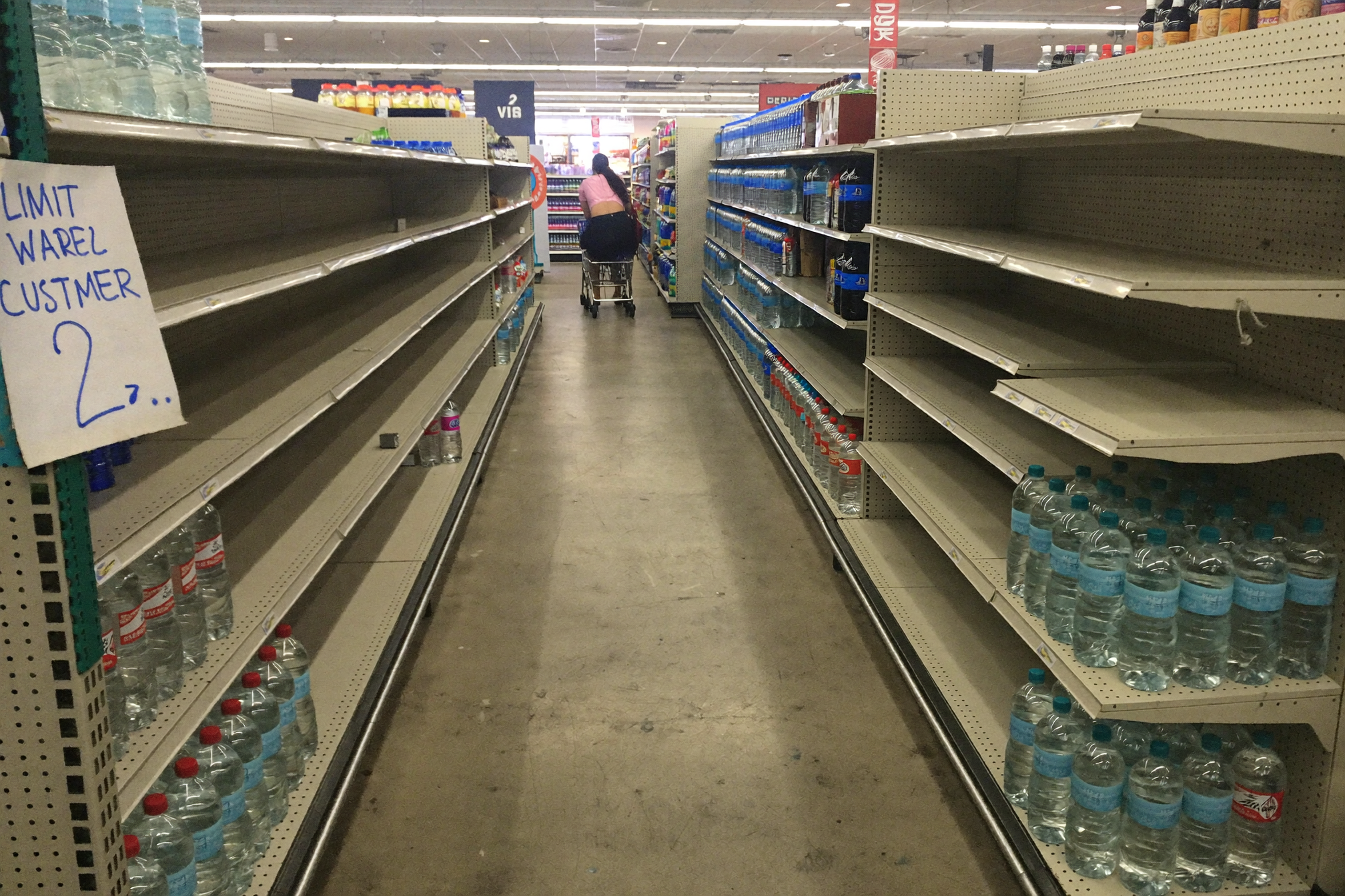 Nearly empty bottled water shelves in a supermarket