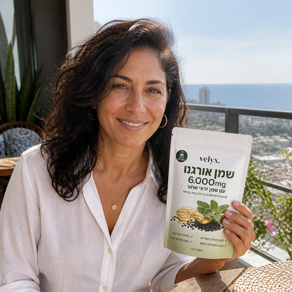 יעל ש., אשה בשנות ה-50 לחייה מחייכת בסלון ביתי, מחזיקה אריזת Velyx, אווירה ביתית חמה