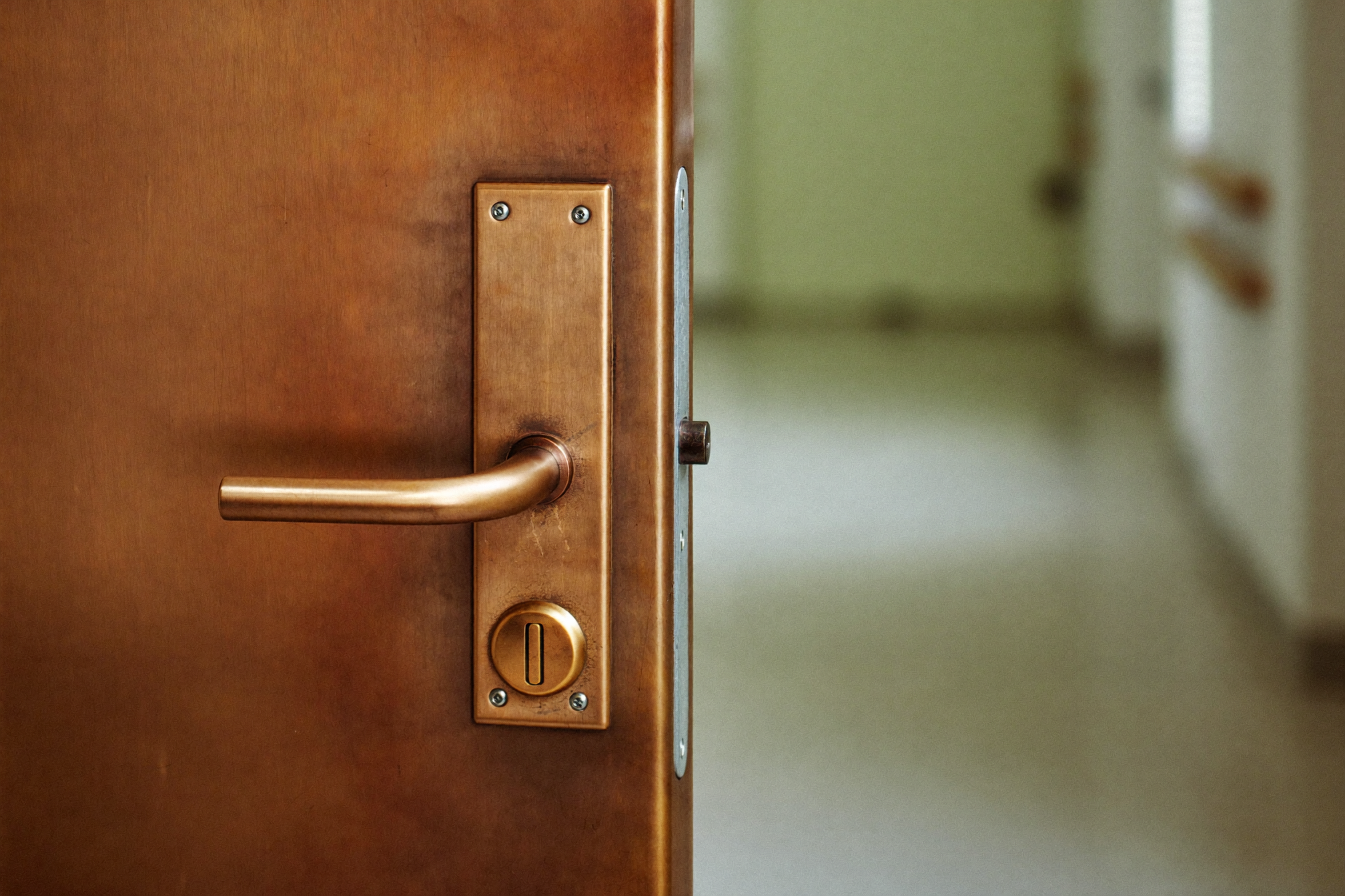 A copper door handle on a hospital corridor door
