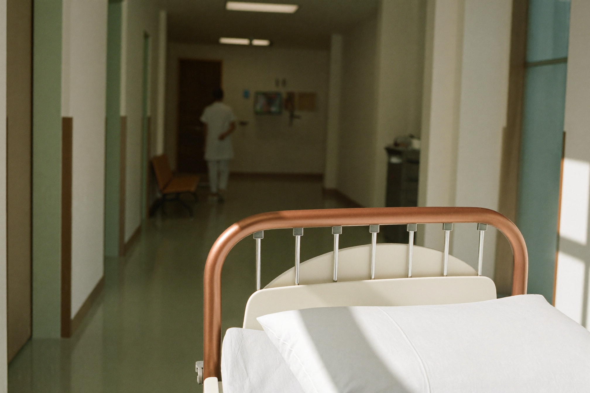 A hospital corridor with a copper handrail and bed rail