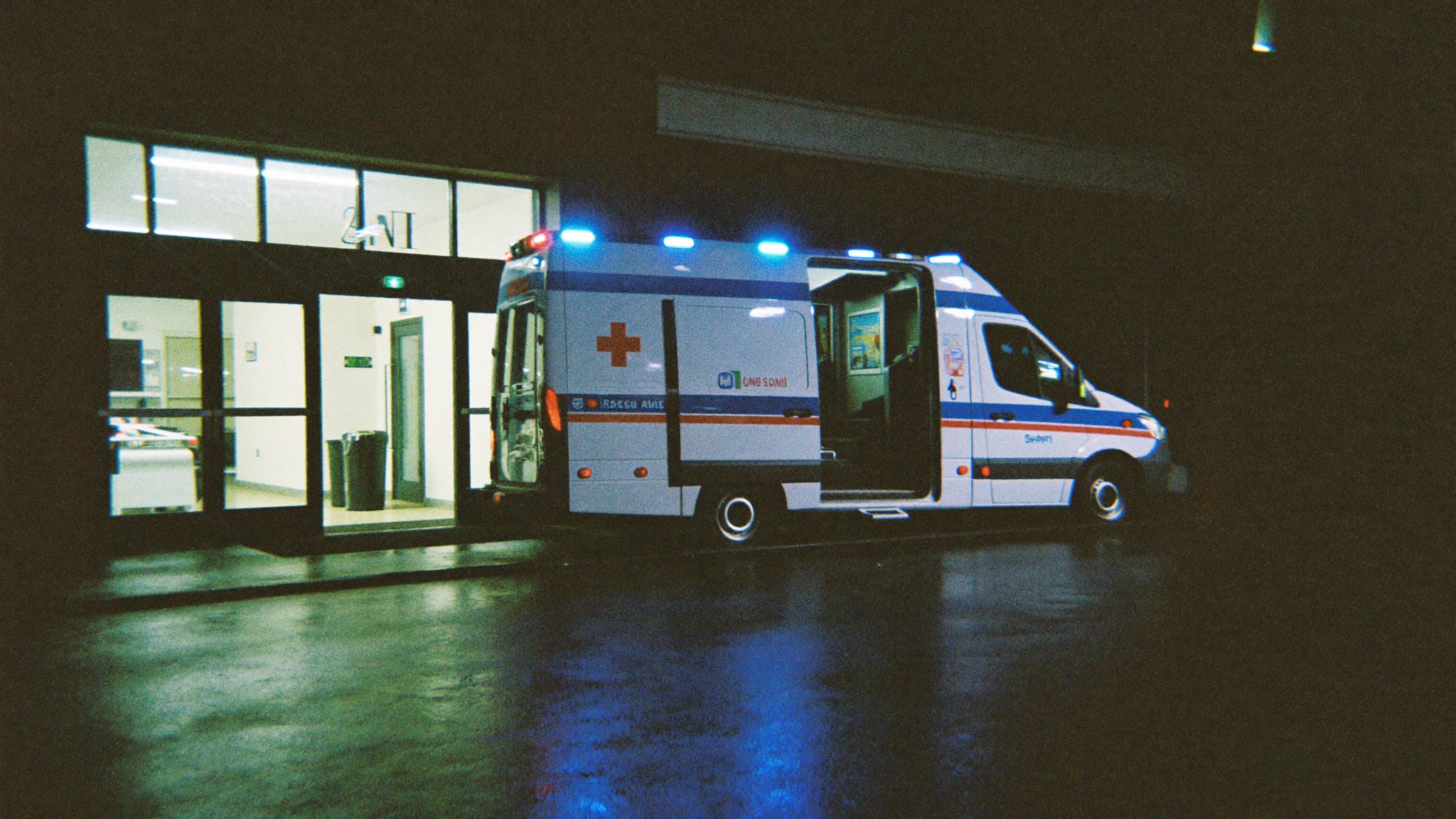 A UK ambulance outside an the ER entrance at night in the rain