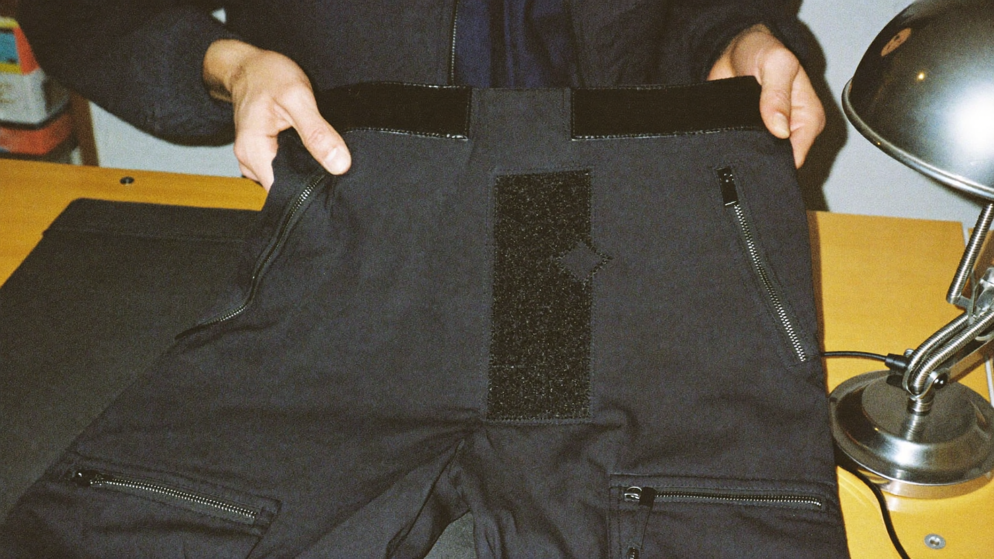 Hands turning the cargo pants inside out to inspect the reinforced panels