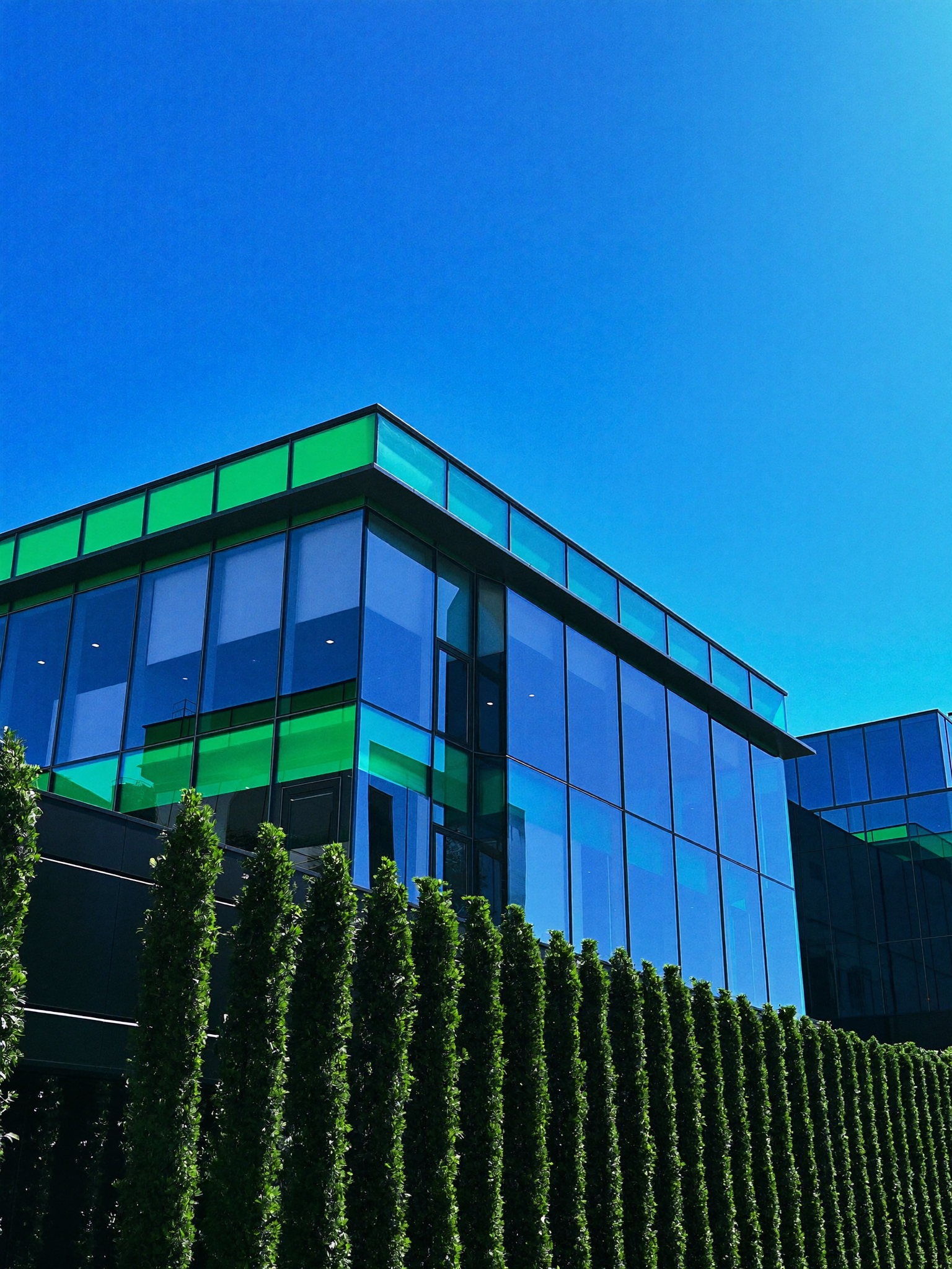 Sleek modern glass office building facade against a brilliant blue sky