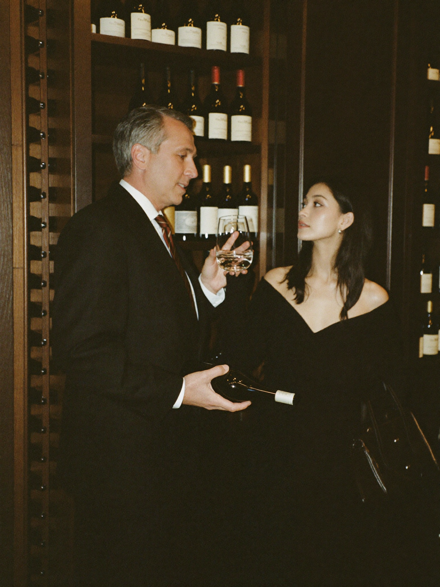 Executive and wine advisor reviewing a fine bottle in a private cellar