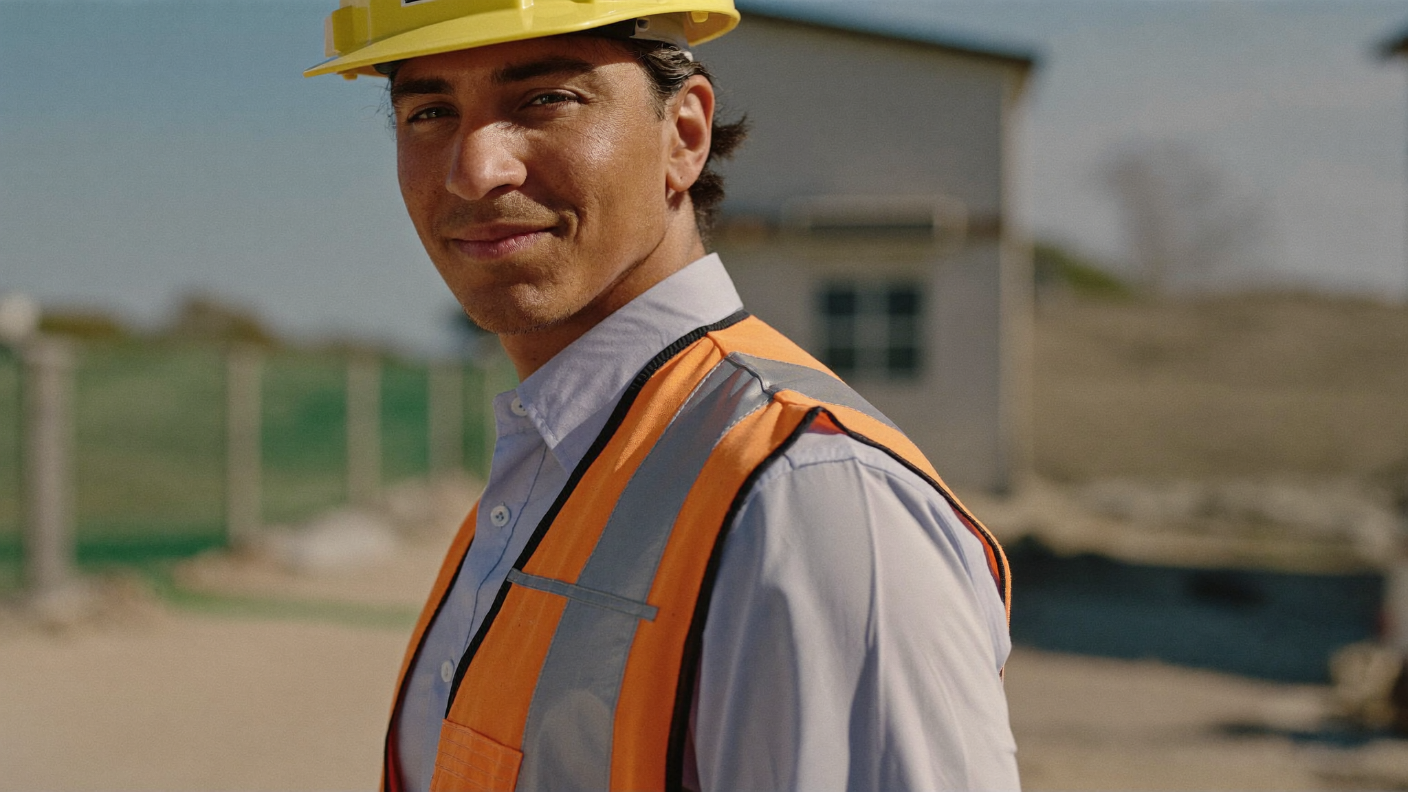 Un trabajador hispano de construcción con casco y chaleco, retrato digno en la obra.