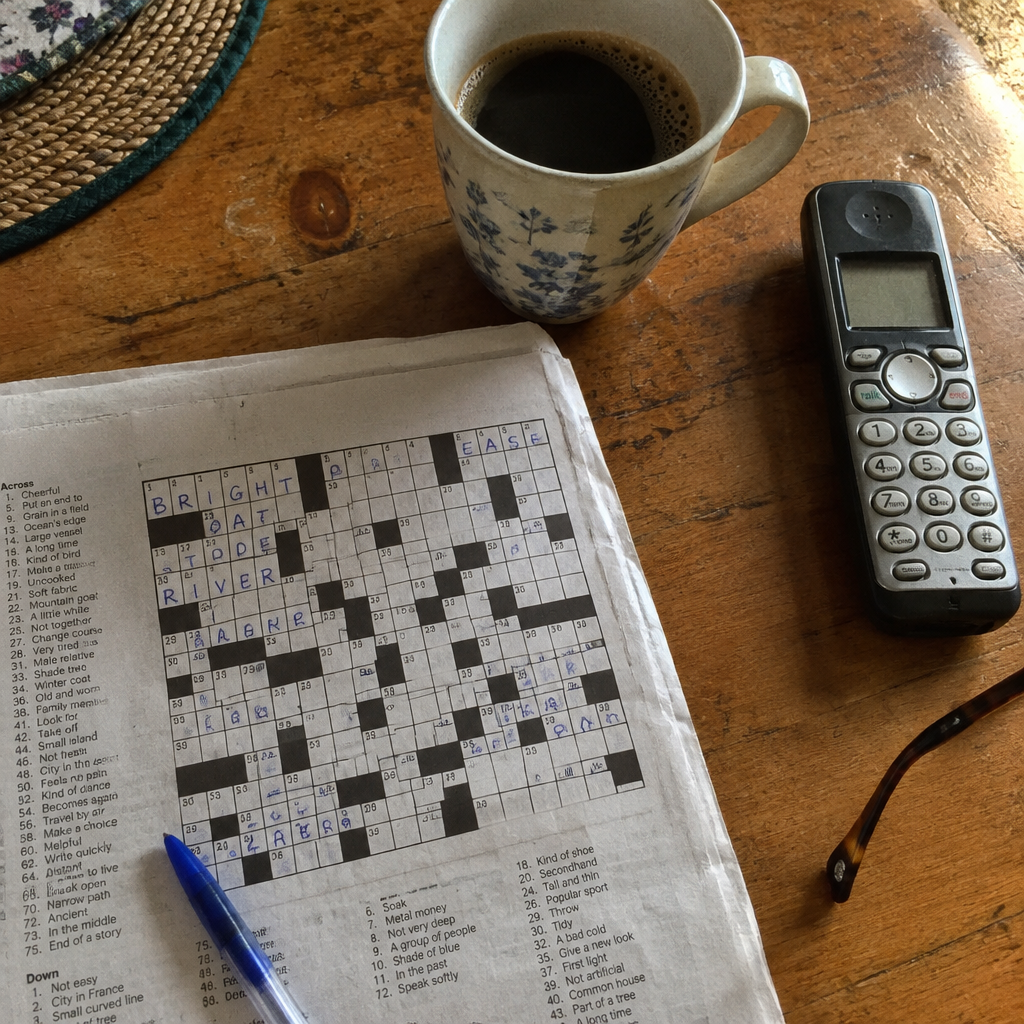 A crossword done in pen and a phone on a kitchen table