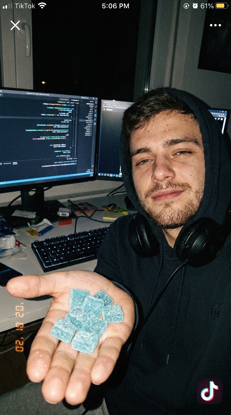 A developer holding Dawnly Focus+ gummies at his desk setup.