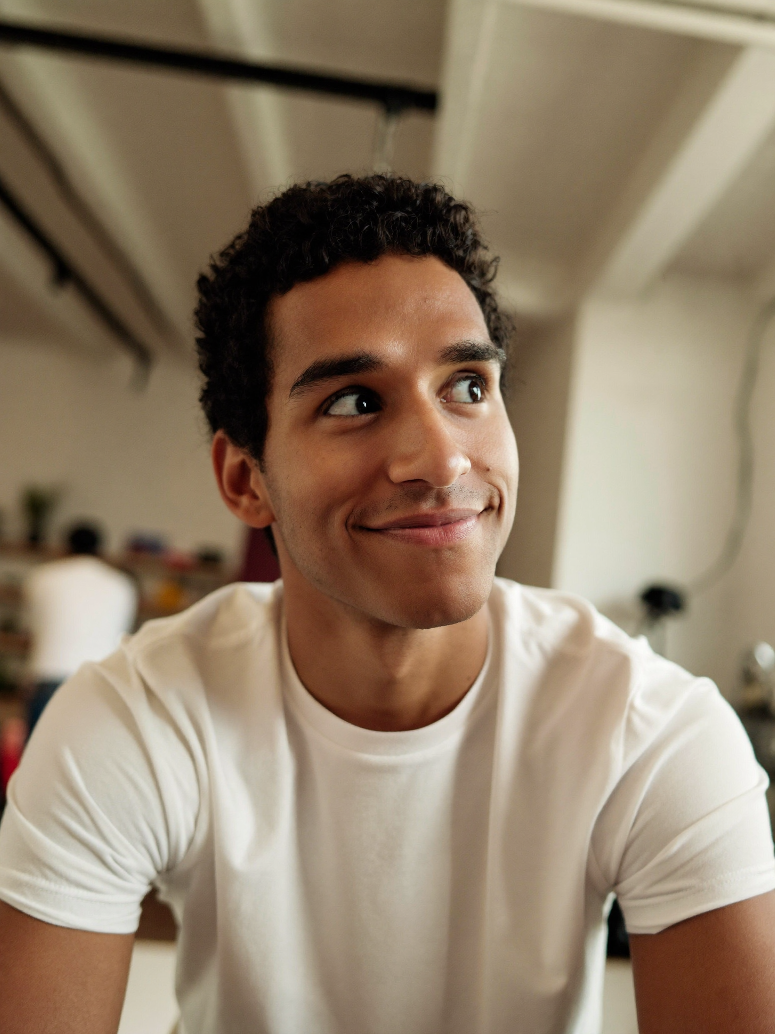 A creative professional smiling thoughtfully in a studio space.