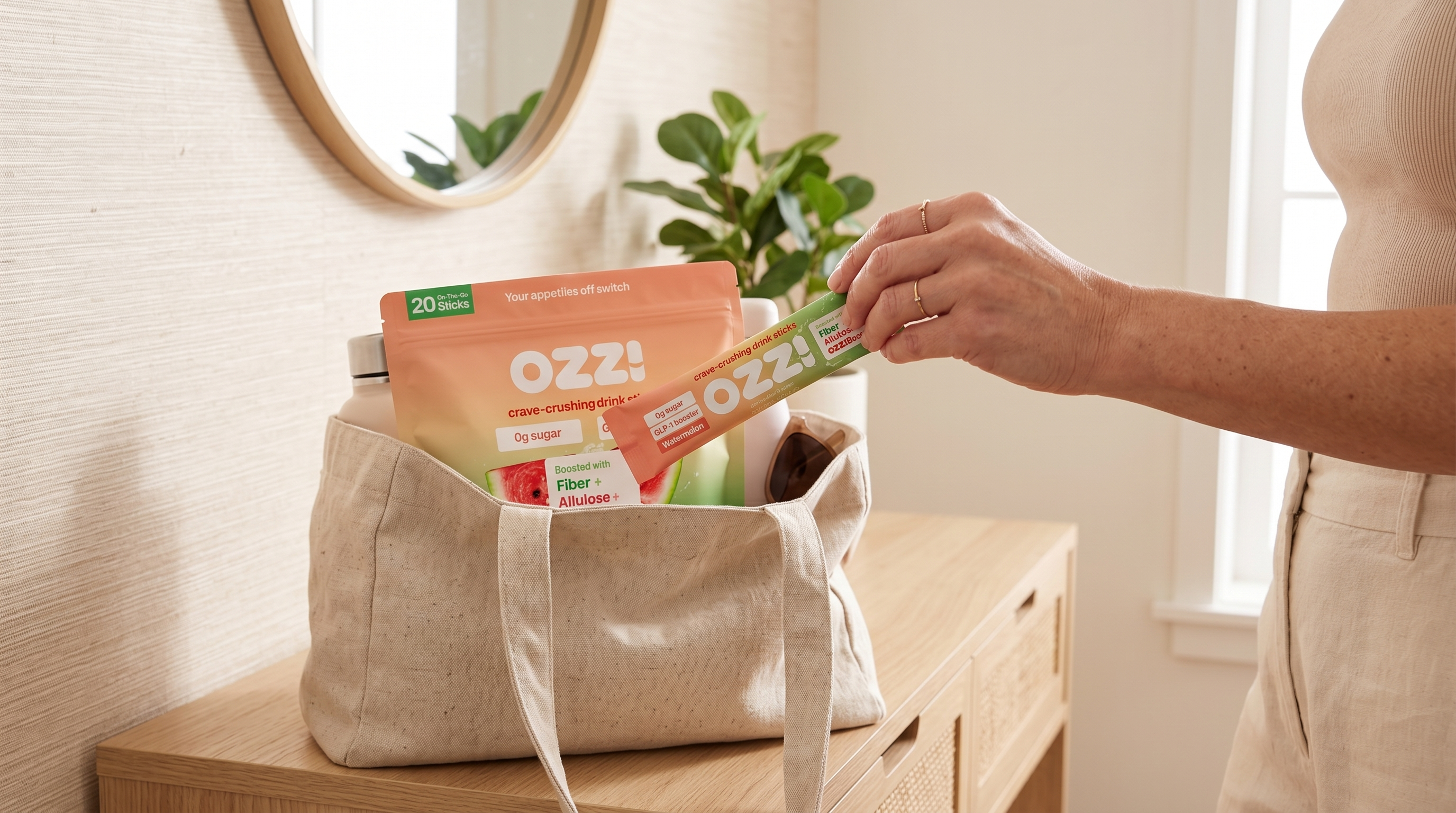 Hand holding a single OZZ! watermelon stick pack over a tote bag with the OZZ! pouch tucked inside