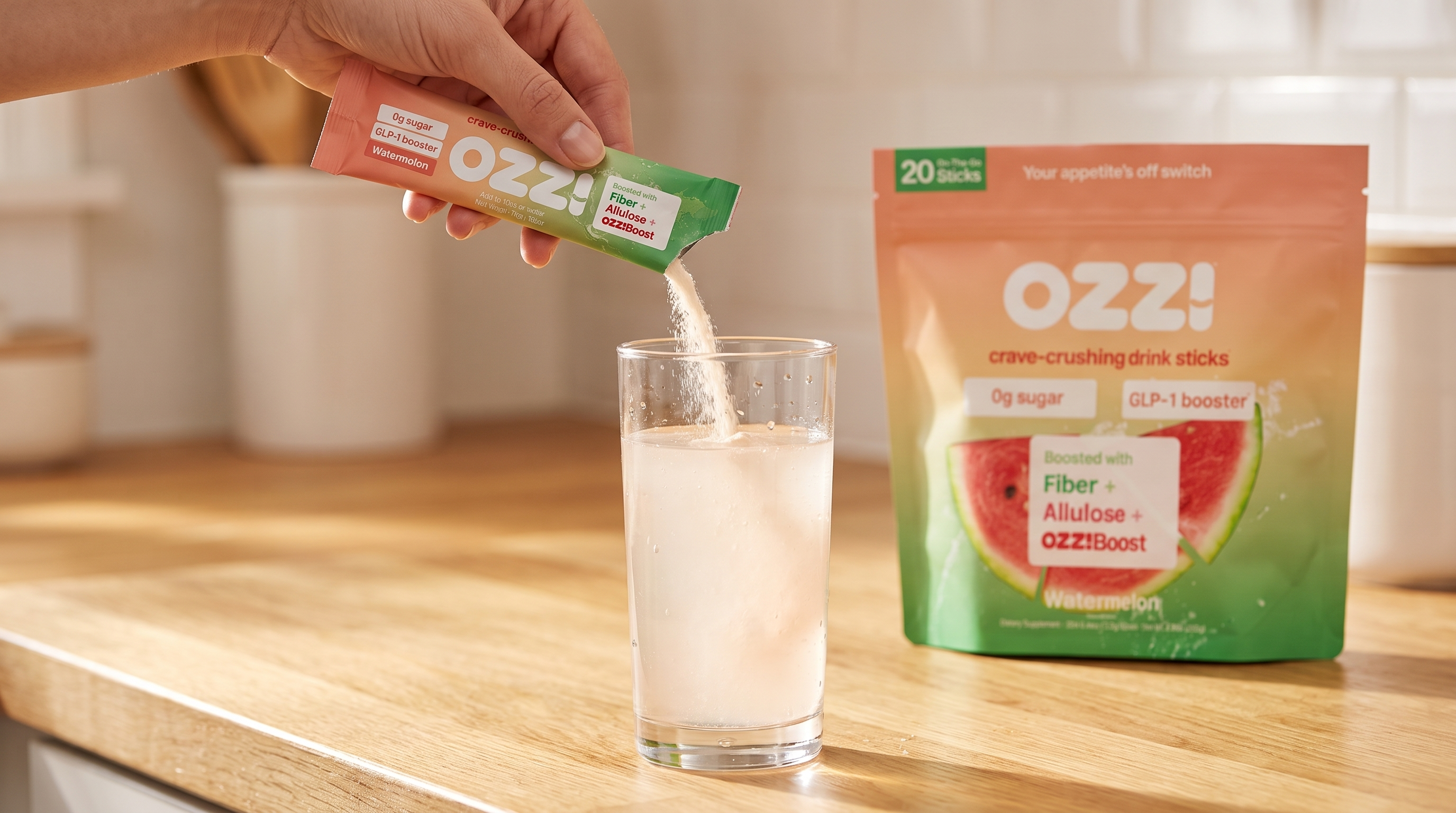 A hand mixing a single Ozzi watermelon drink stick into a glass of cold water on a kitchen counter