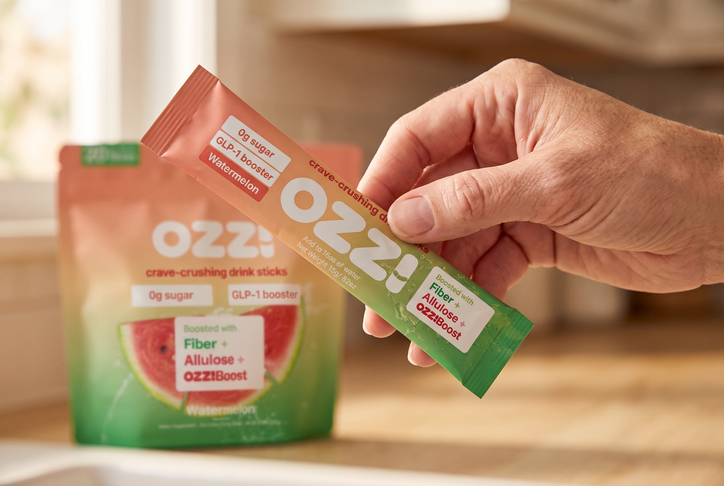 A hand holding a single Ozzi watermelon stick pack