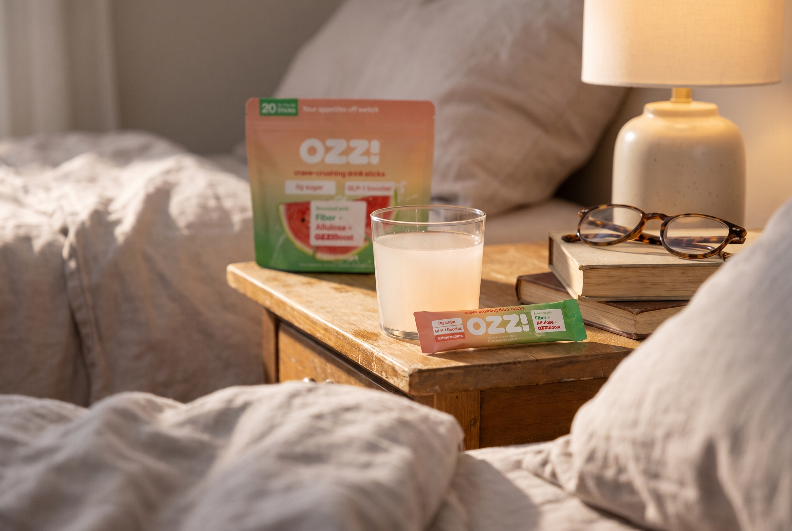 A bedside table at morning with books, reading glasses and a glass of prepared Ozzi