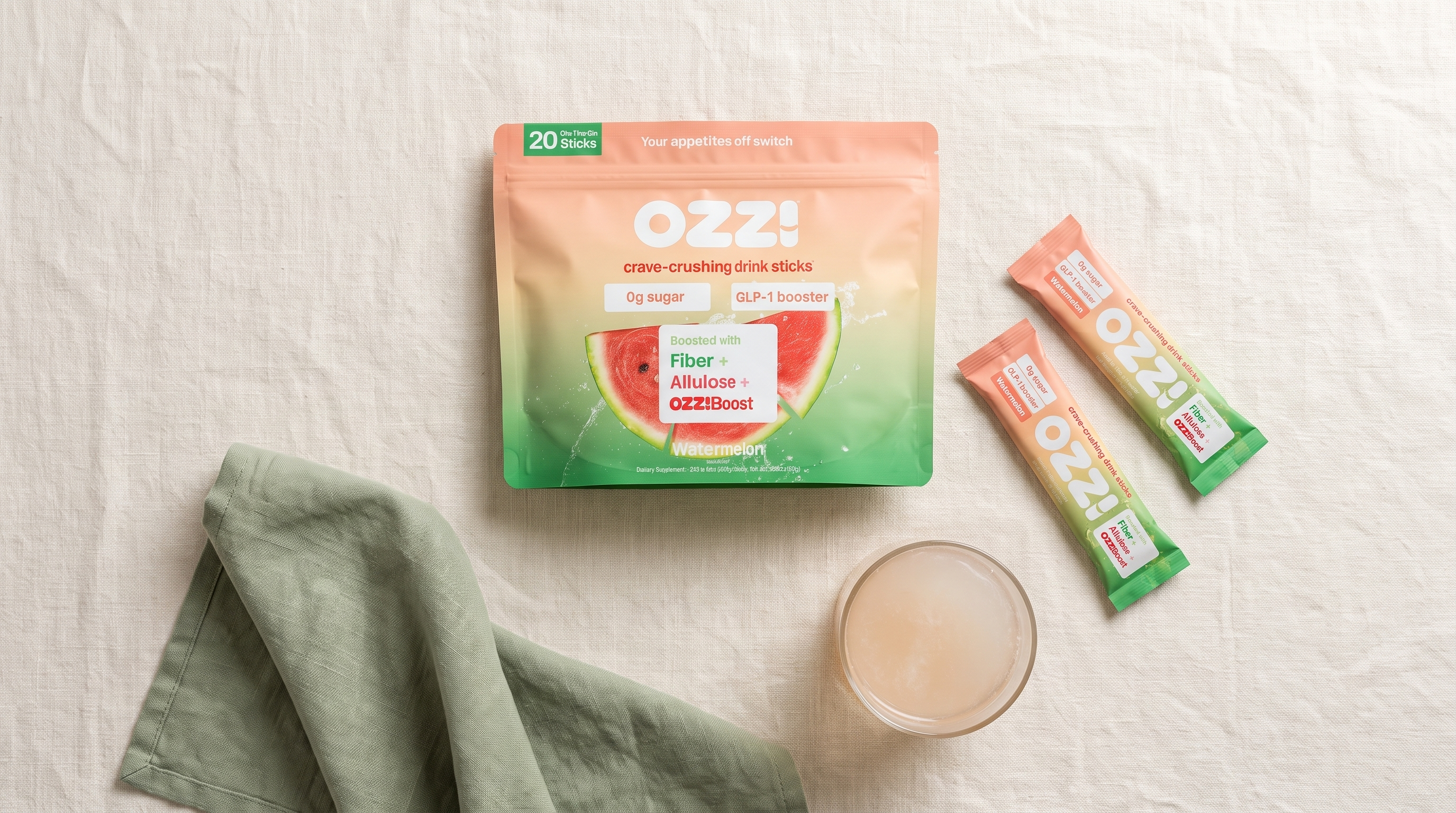 An Ozzi Crave Crusher pouch and stick pack on a desk beside a glass of the prepared drink