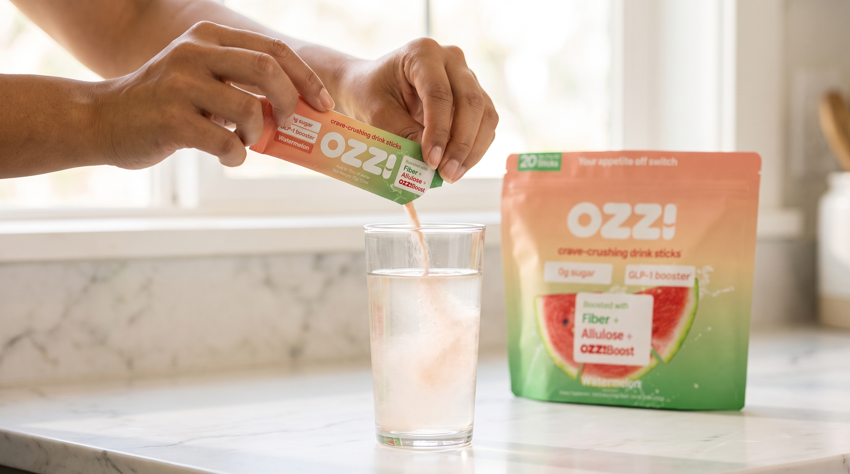 Hands tearing open an Ozzi watermelon stick pack over a tall glass of water on a marble kitchen counter, with the pouch visible in the background