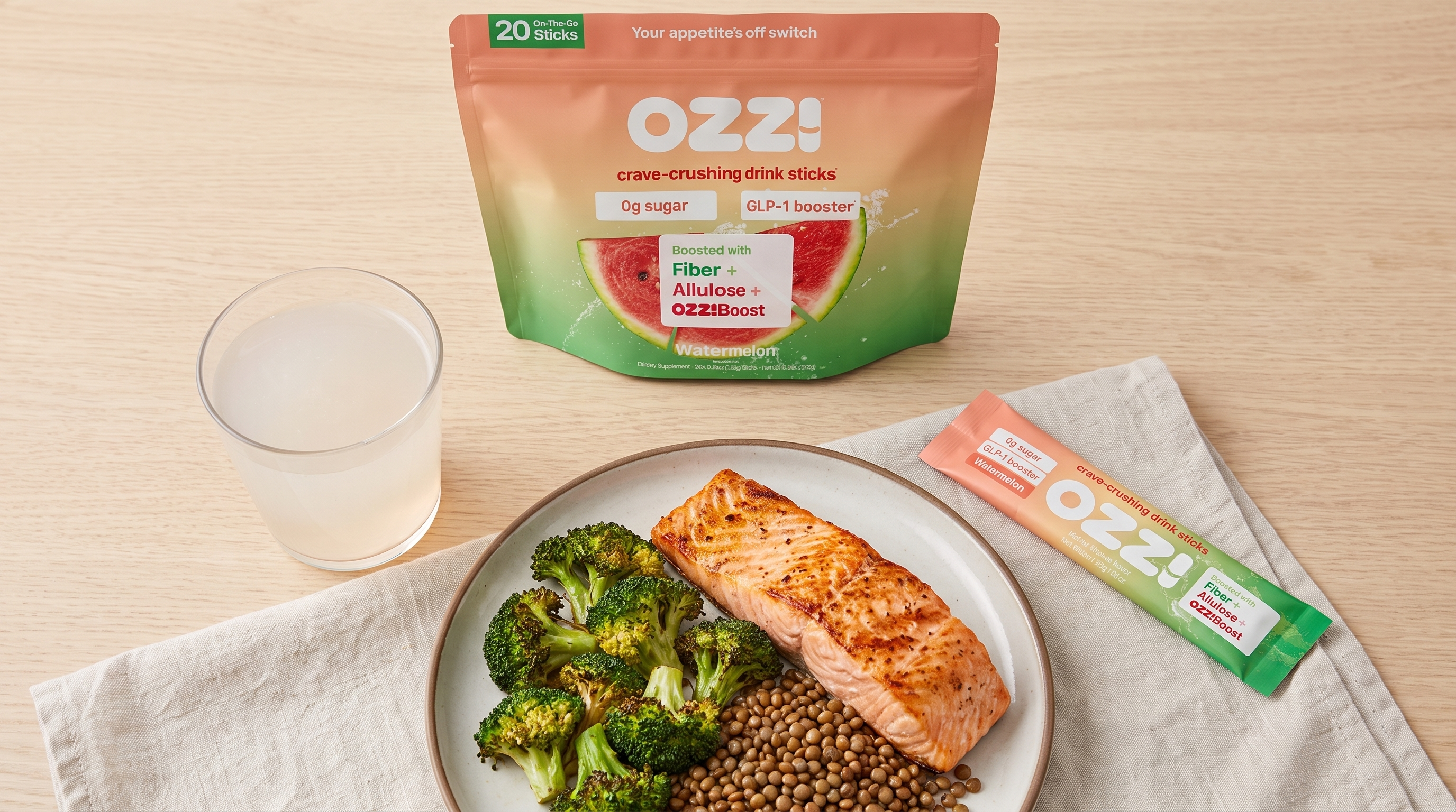 Overhead view of a balanced meal beside an Ozzi stick pack, pouch, and a glass of the prepared drink