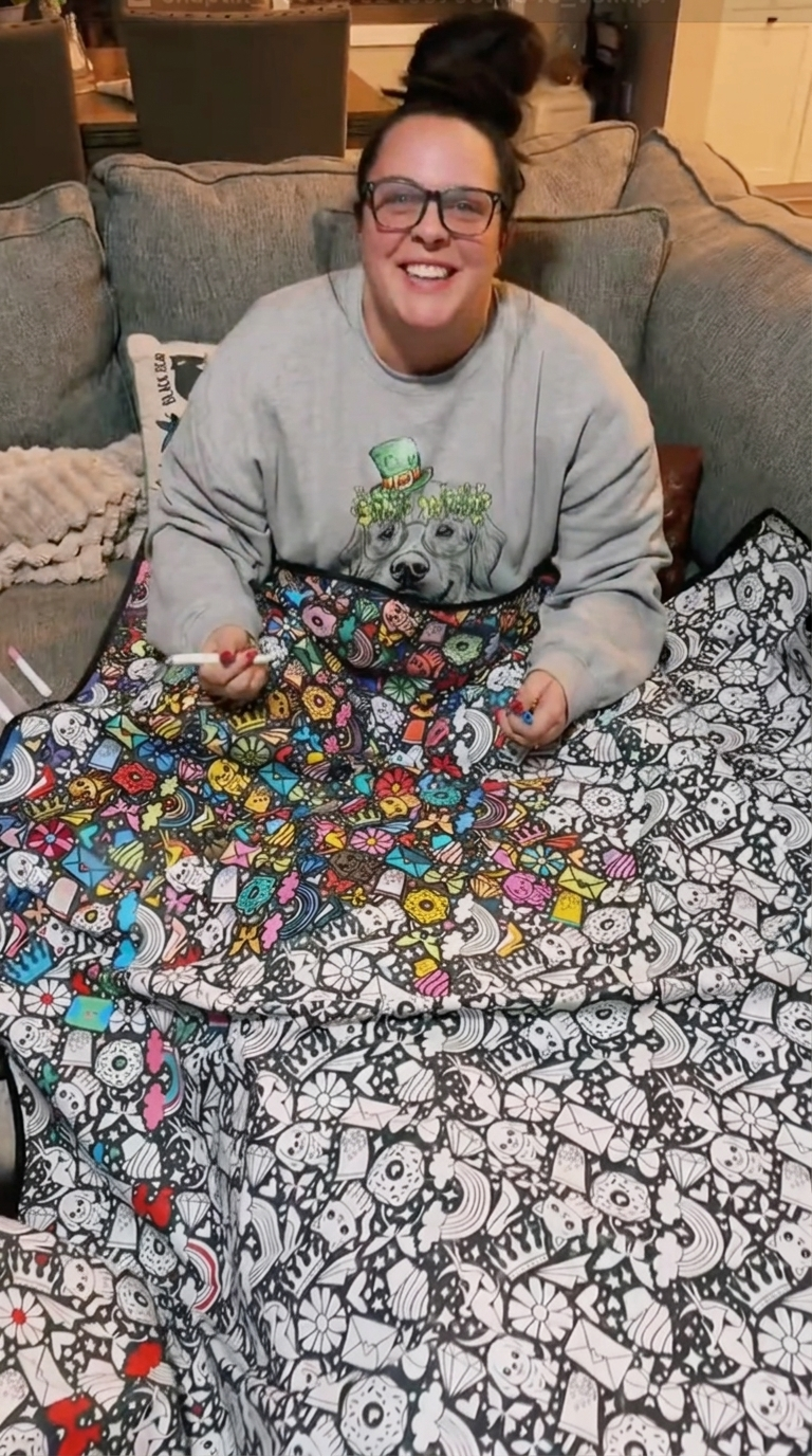 Kundin mit ihrer bunt ausgemalten Kreativdecke (Totenkopf-Muster)