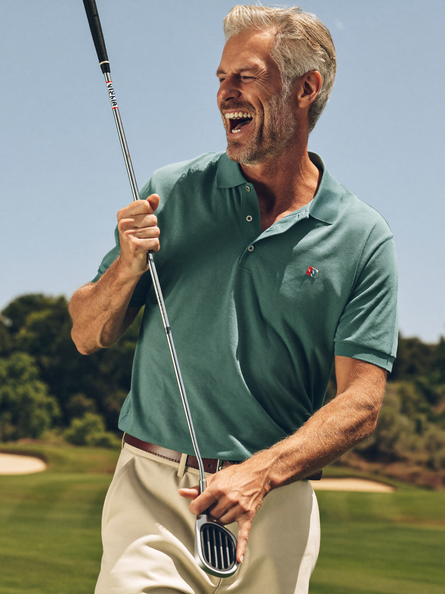 Confident active retired man laughing on a sunny golf course
