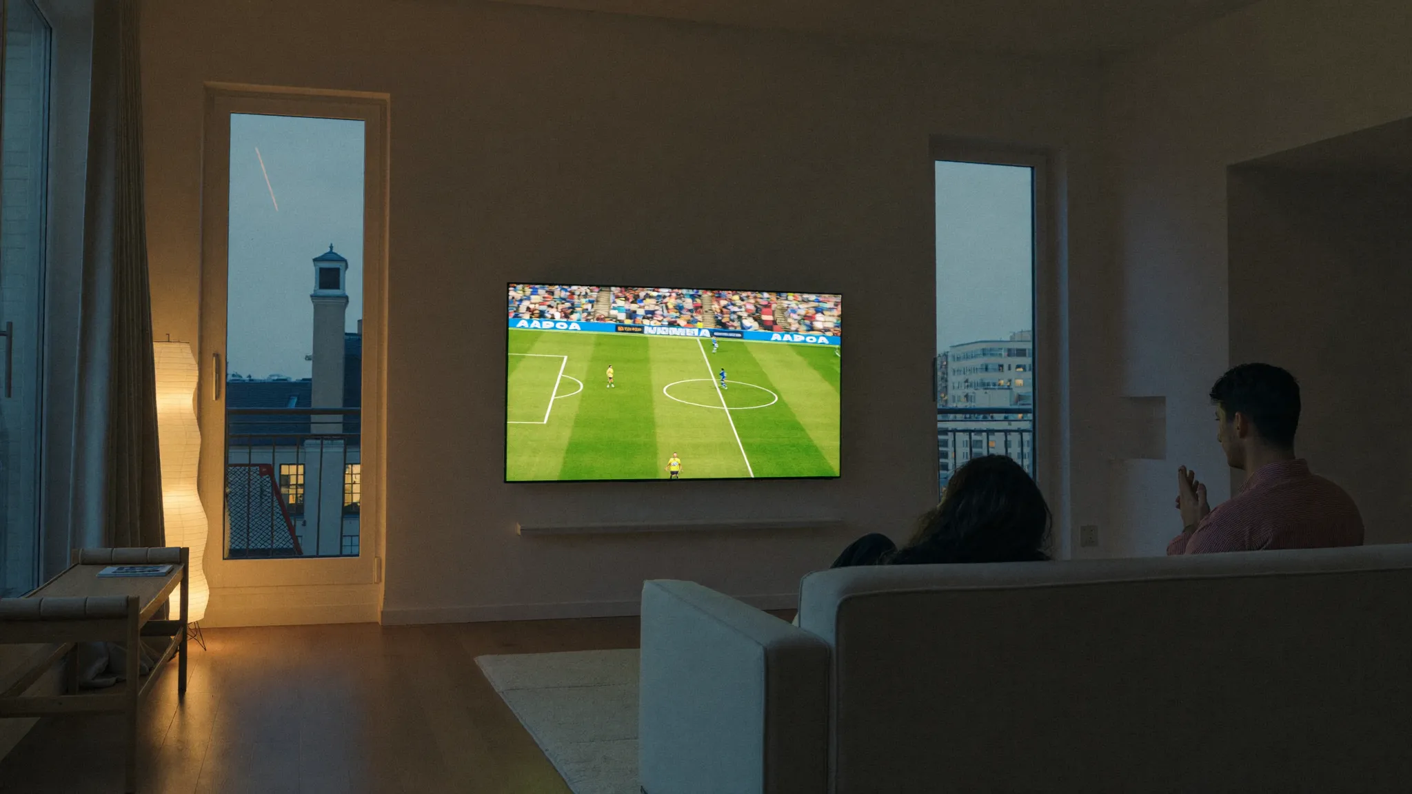 Deux amis dans un salon devant un match de football en 4K diffusé grâce à un abonnement IPTV