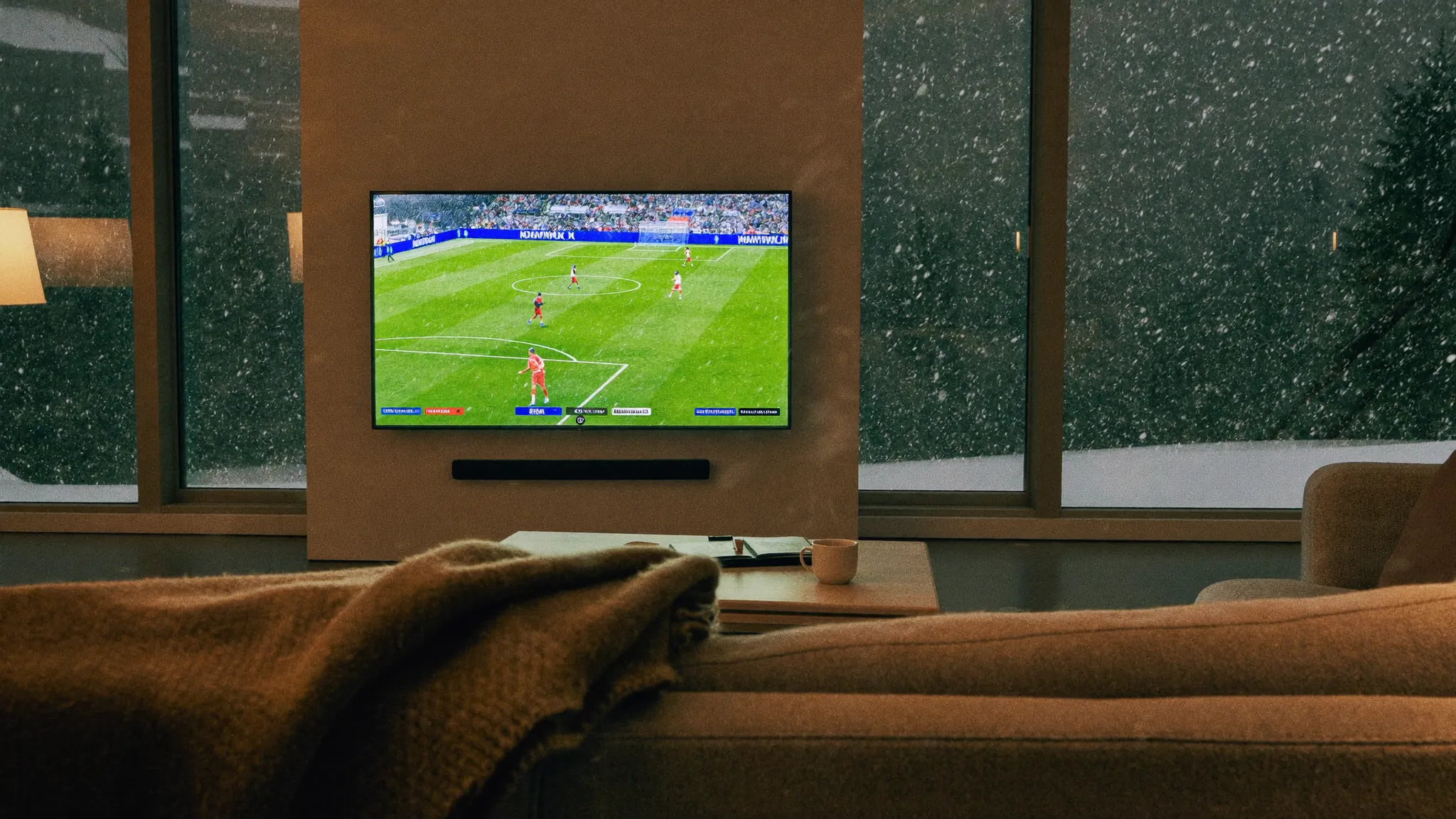 Soirée d'hiver dans un salon, neige dehors, match de football en 4K sur la télévision grâce à un abonnement IPTV 12 mois