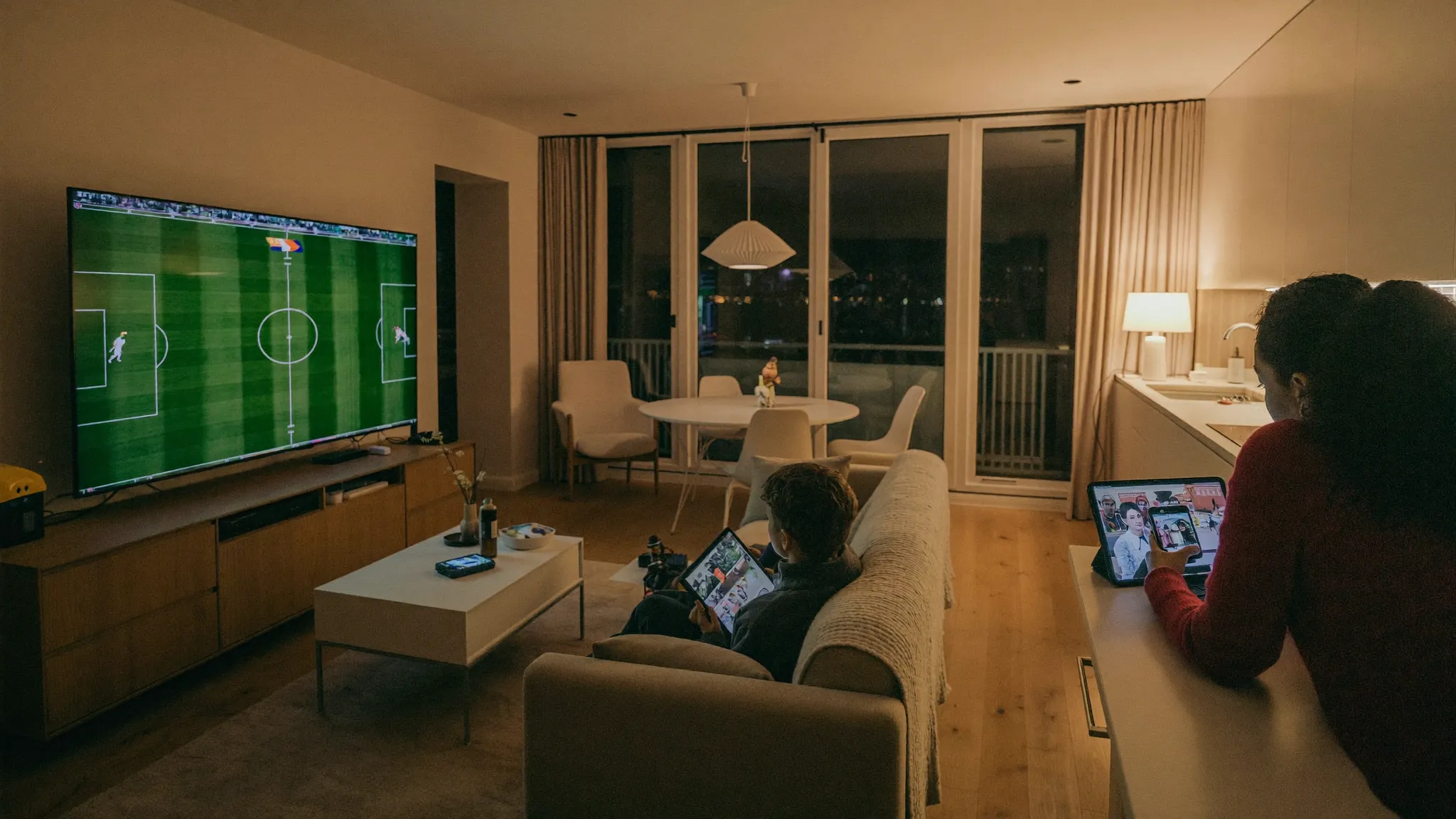 IPTV multi-écrans : trois écrans allumés en même temps dans un appartement, télévision, tablette et téléphone