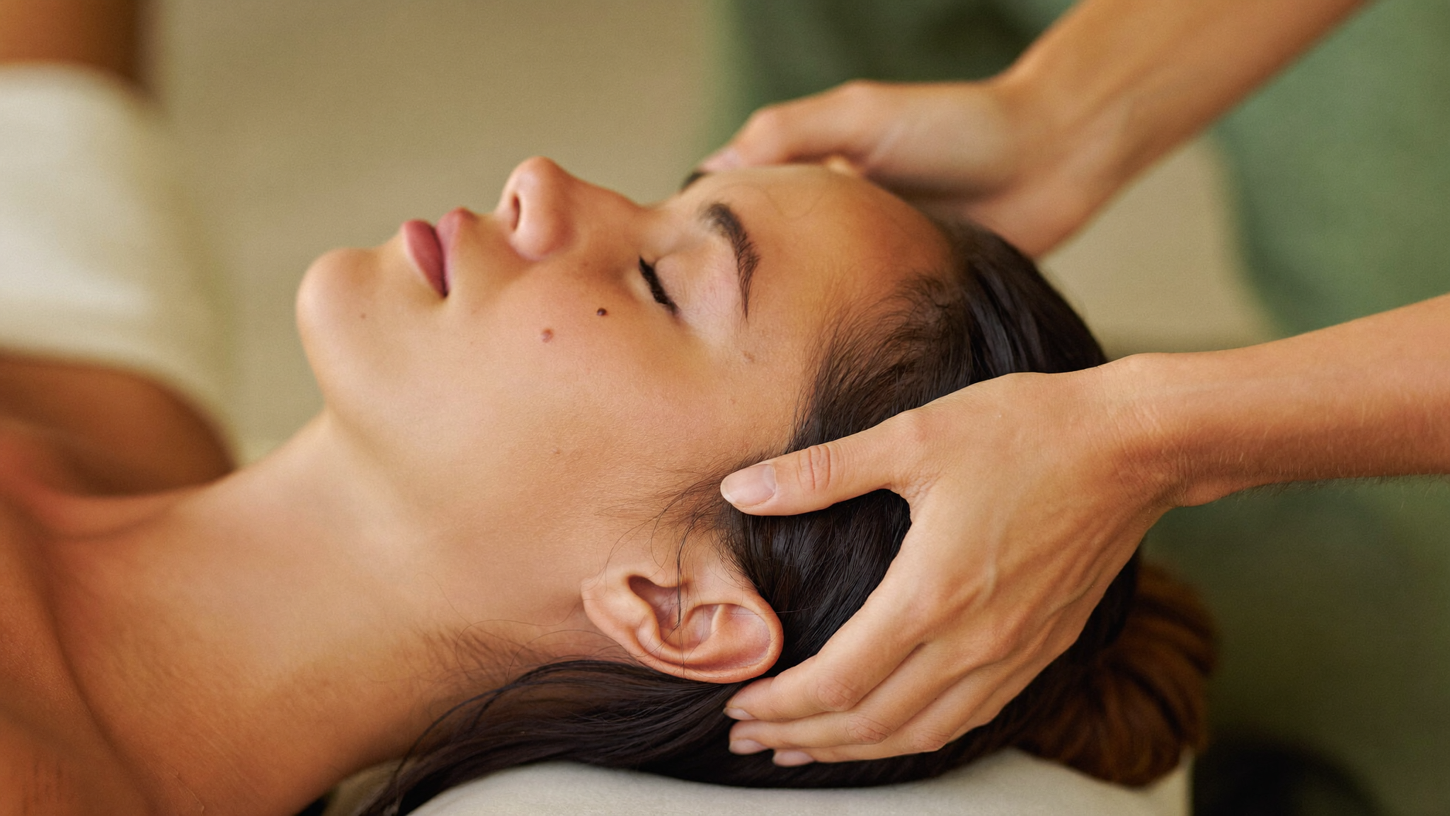 A woman relaxing with her eyes closed during a dry scalp and head massage at Mindful Women Spa in South Ogden, UT