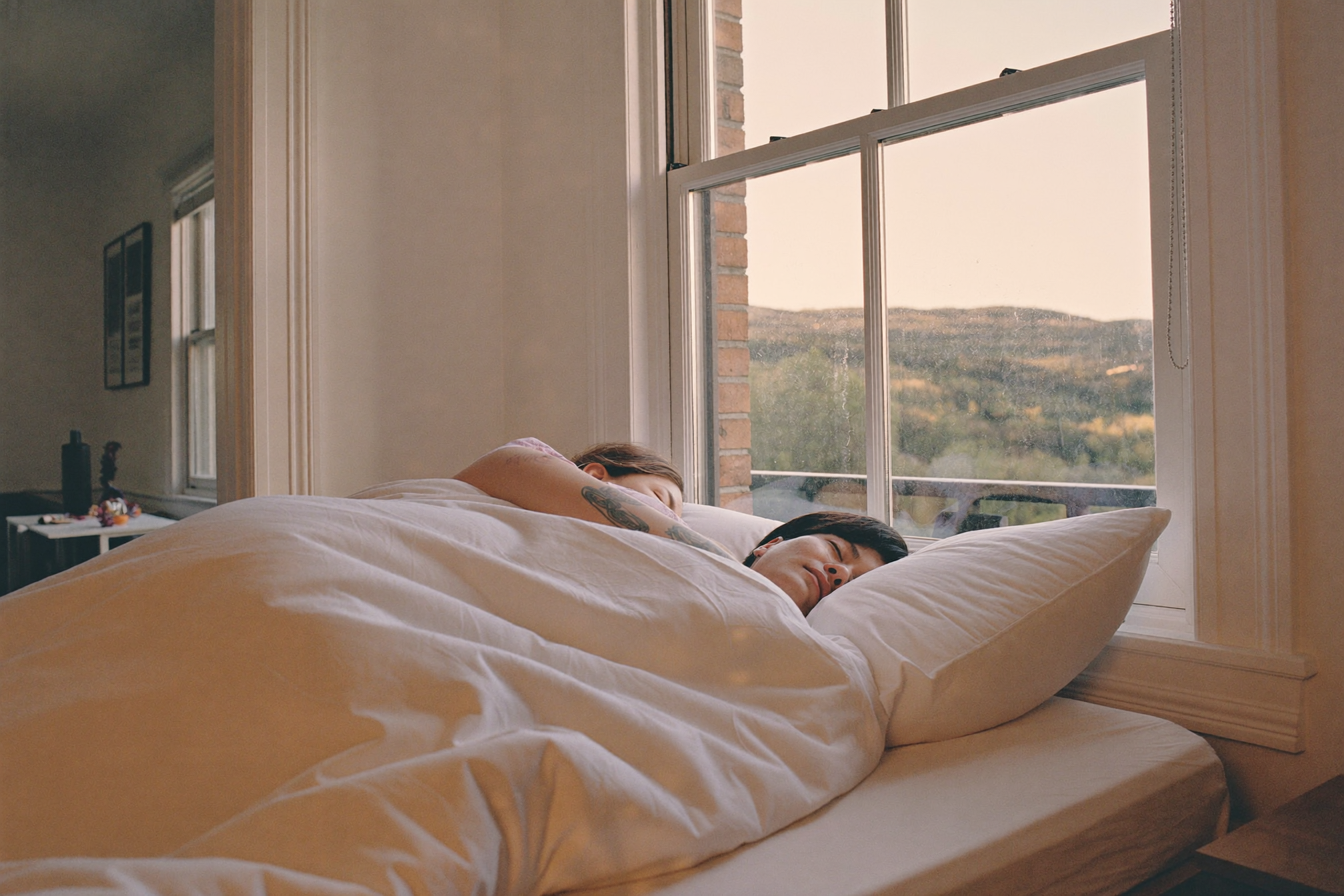 A couple sleeping peacefully under the covers at dawn
