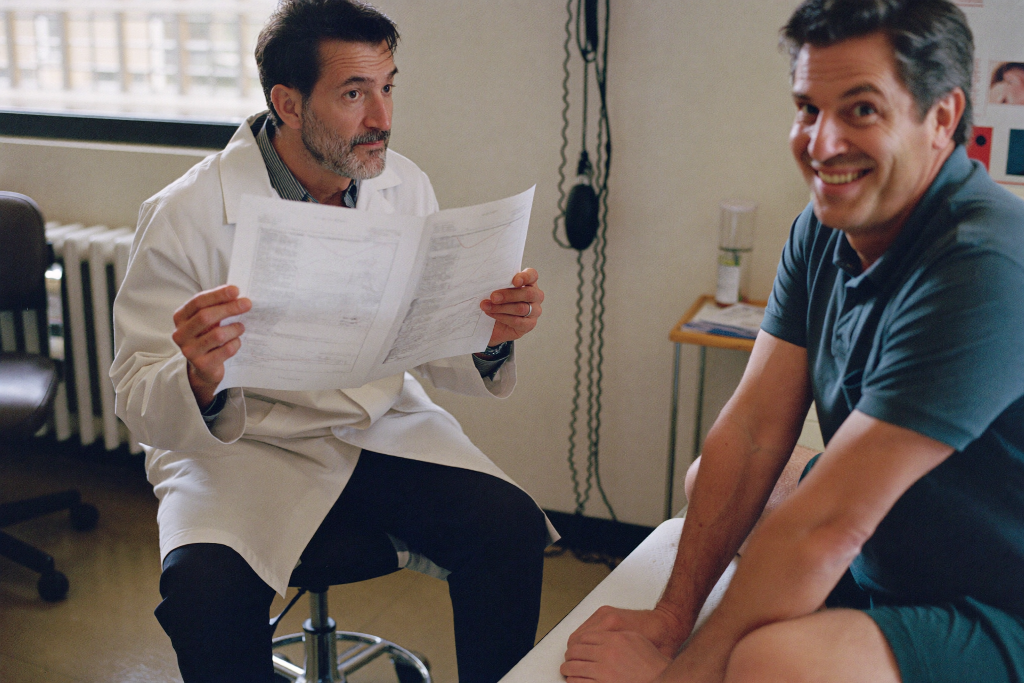 A doctor looking up from a lab printout at his patient