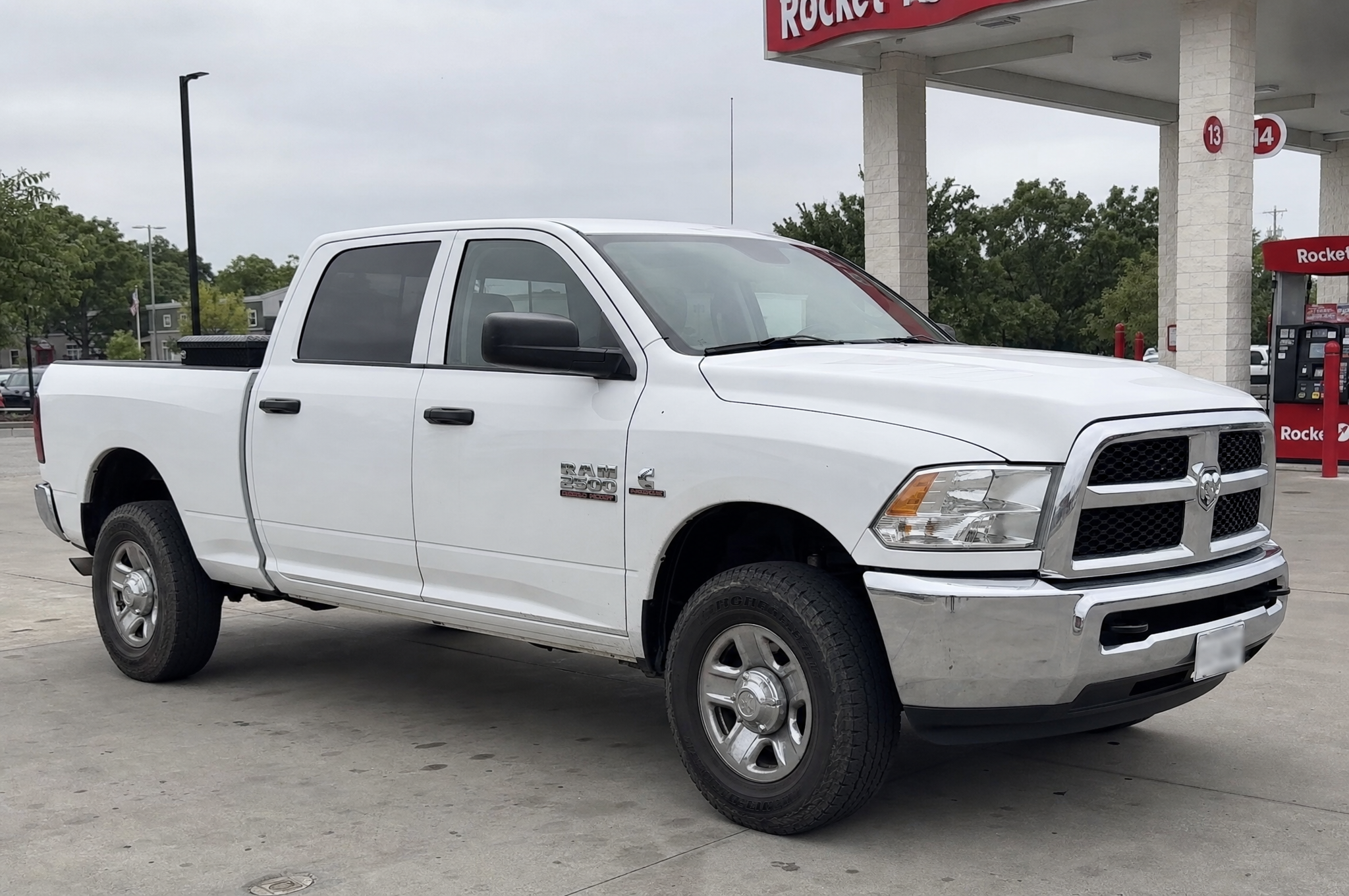 Stock white Dodge Ram 2500 Cummins at a gas station on an overcast day