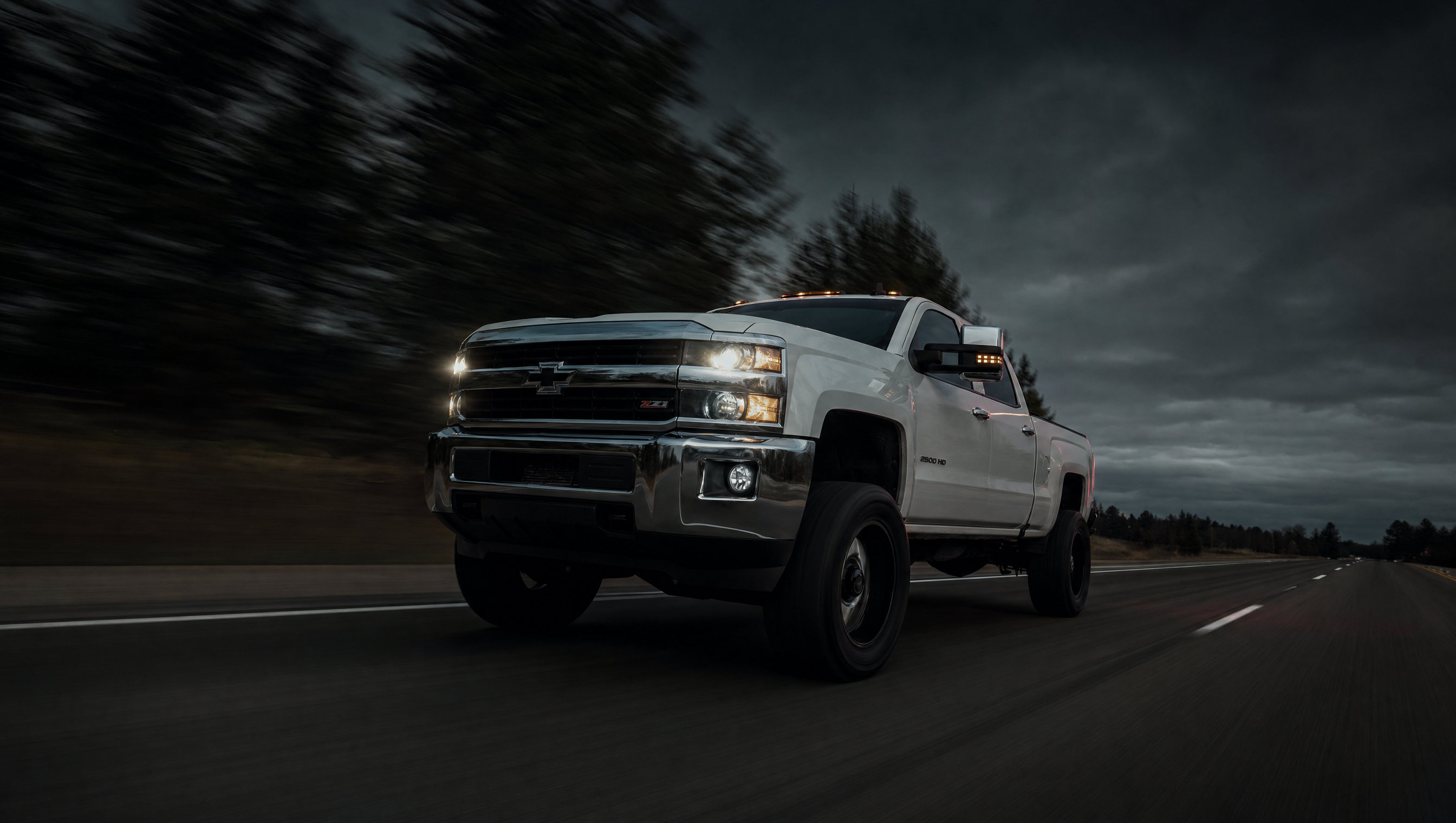 White Chevy Duramax at night, headlights on
