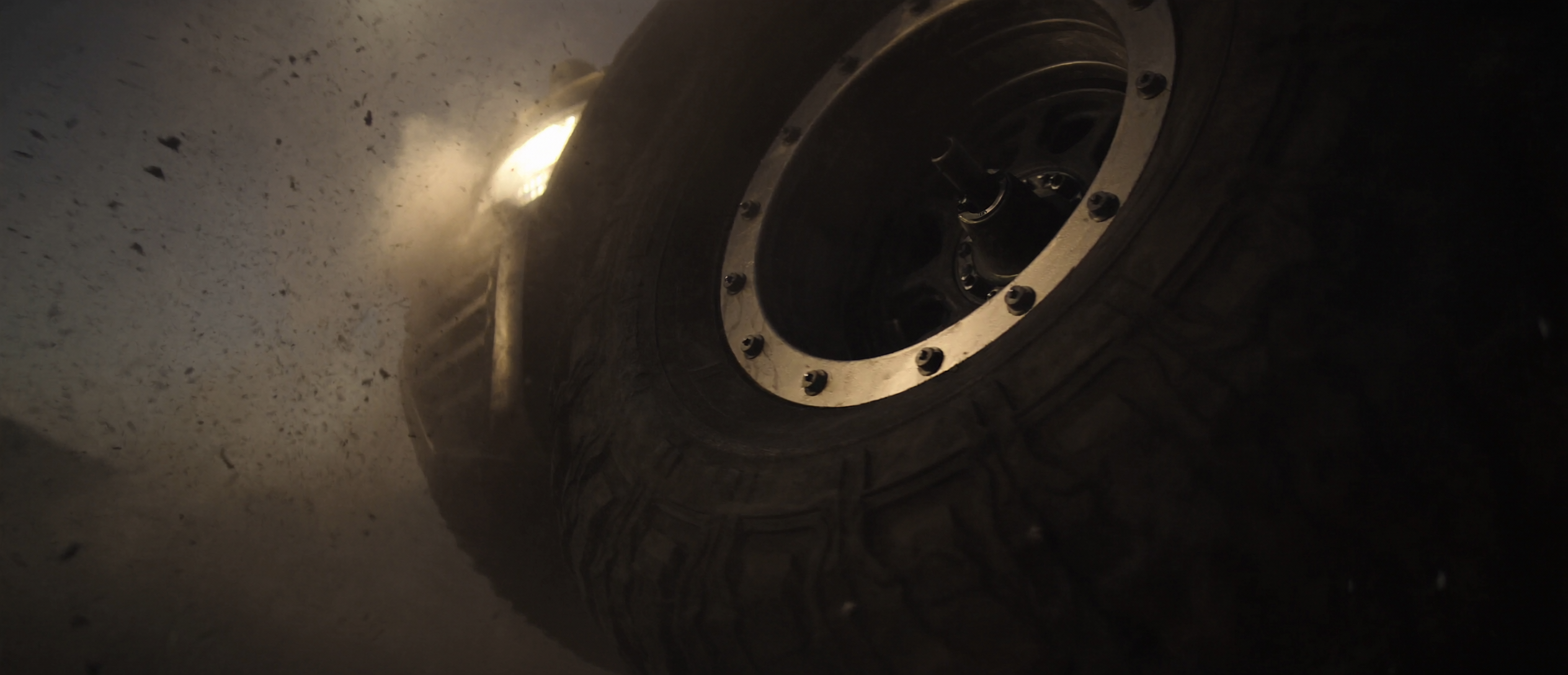 Off-road beadlock wheel and all-terrain tire kicking up dust